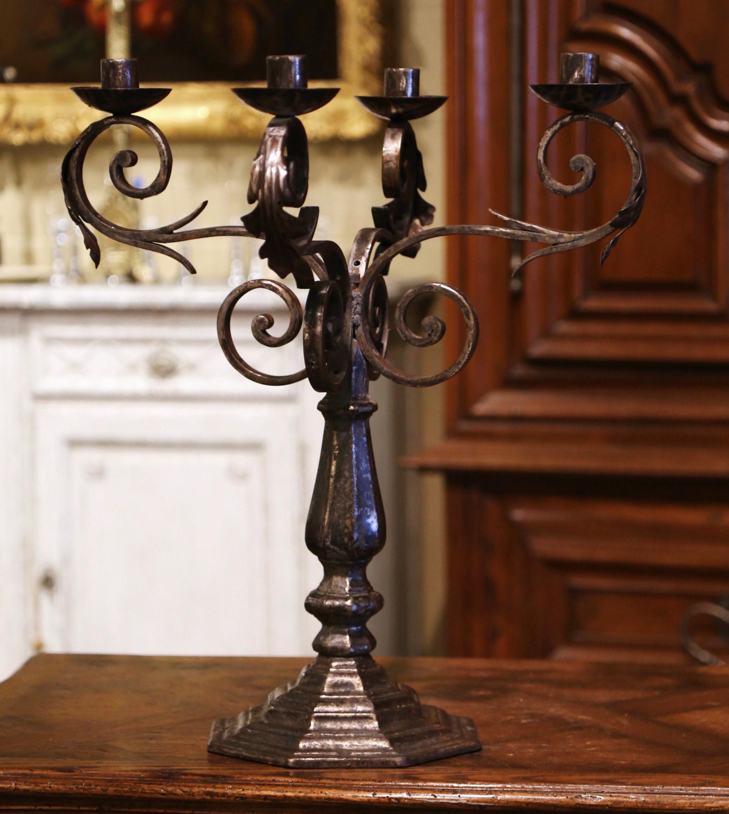 Decorate a mantel or a buffet with this elegant antique four-arm candelabra. Crafted in southern France circa 1780, the large forged piece stands on an octagonal base over a central turned stem, and features four scrolled arms decorated with
