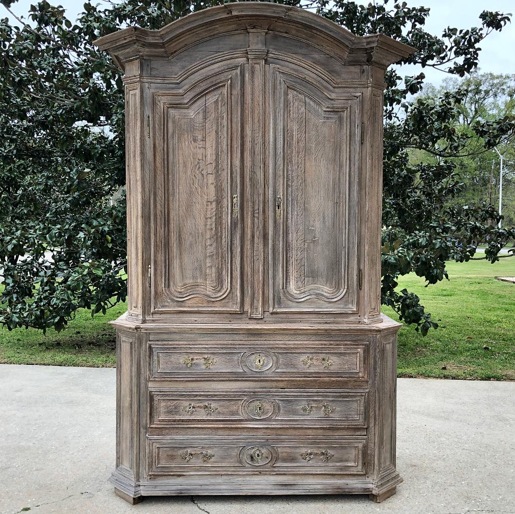 18th century French Louis XIV whitewashed wardrobe will command a stately presence in any room! The boldly arched crown is composed of multiple tiers of molding, which culminate in the mitered corners on each side. The arches of the doors underneath