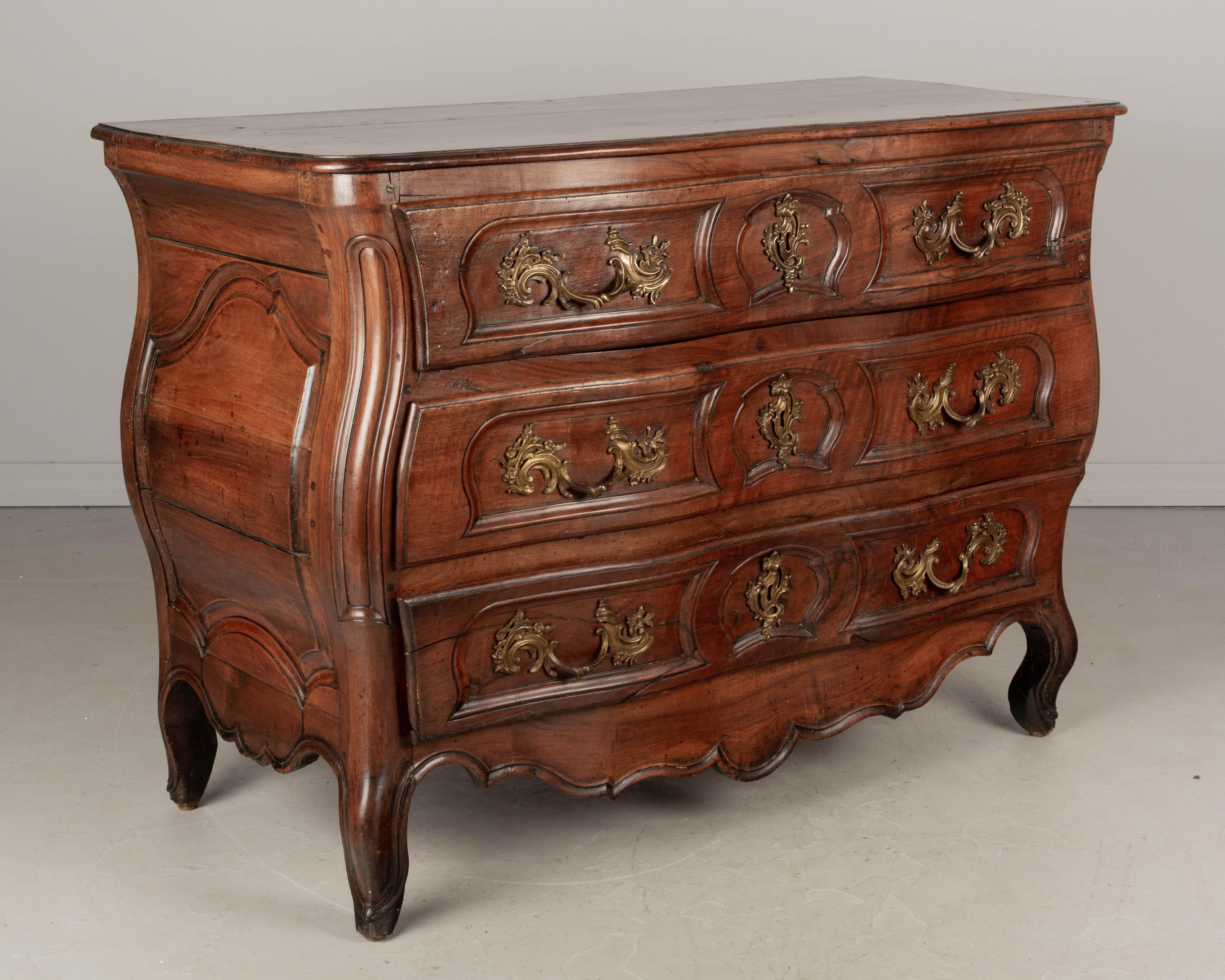 An 18th century French Louis XV commode, or chest of drawers, from the Bordeaux region made of solid walnut. Nice proportions with bold bombé form and serpentine front. Three dovetailed drawers with original cast bronze hardware (lower right handle