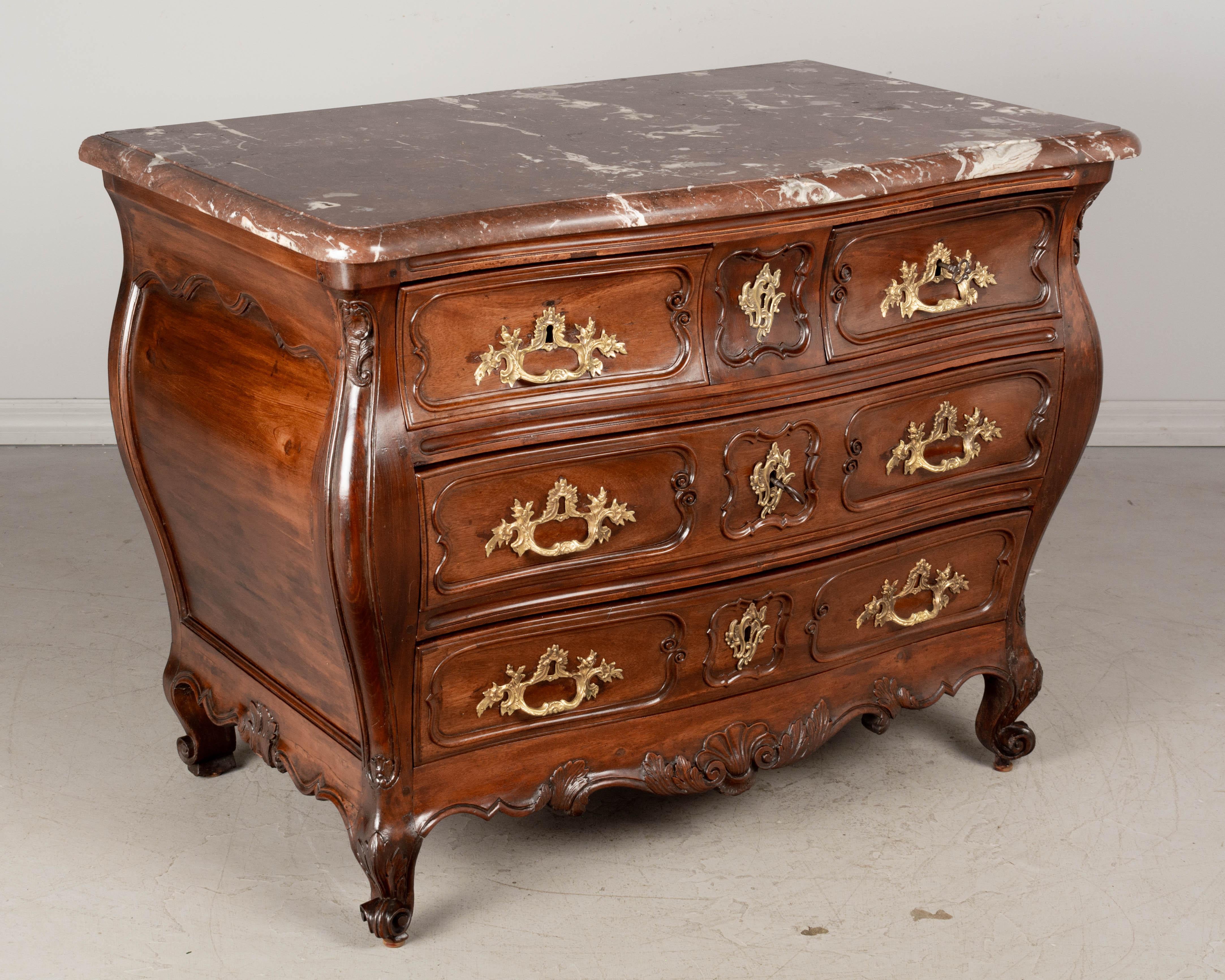 Una commode, o cassettiera, francese Luigi XV del XVIII secolo, proveniente dalla regione di Bordeaux e realizzata in mogano massiccio. Belle proporzioni e forma bombata con fronte a serpentina. Il piano in marmo Rouge Royale originale ha uno