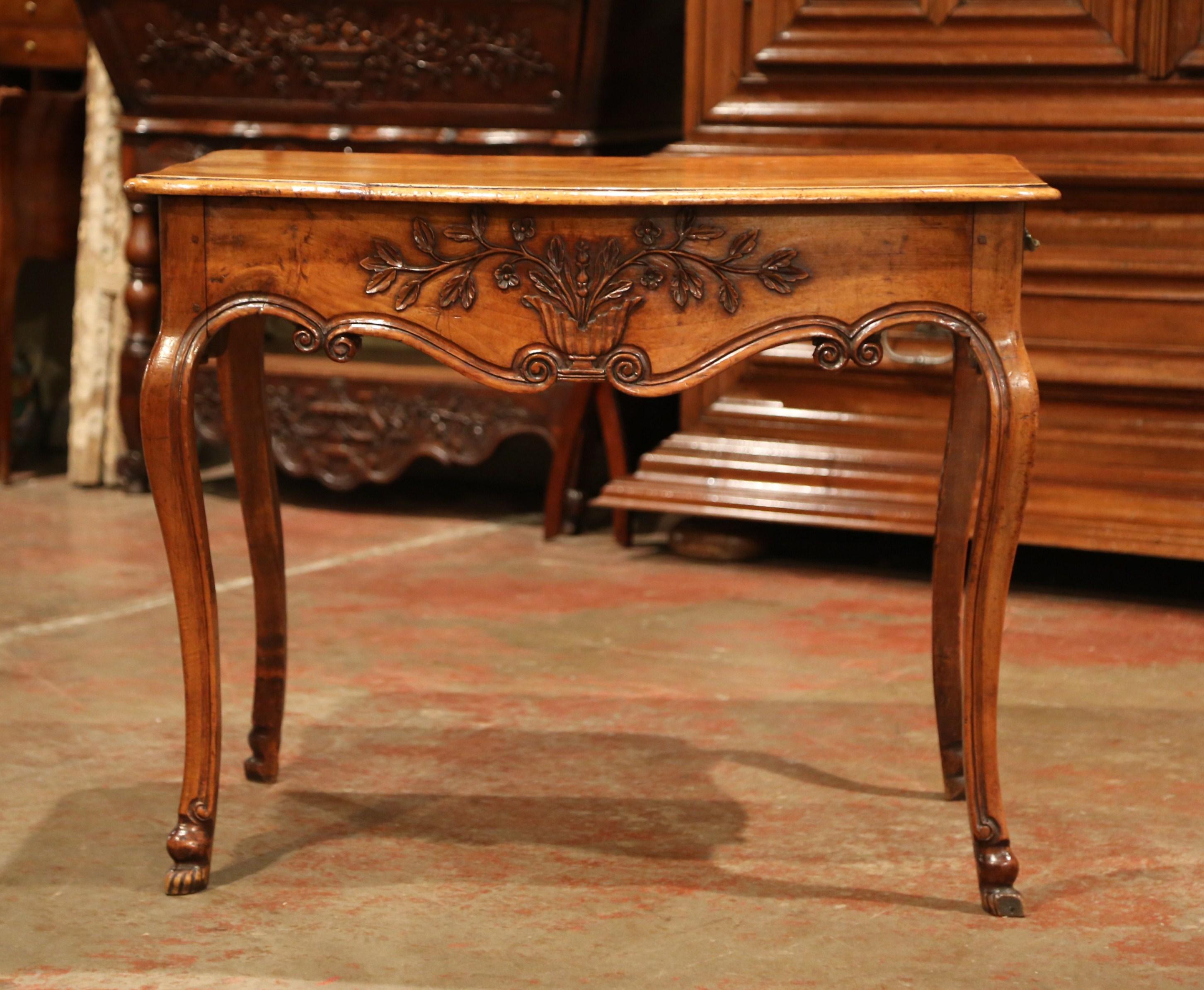 Decorate a bedroom or a living room with this elegant antique fruitwood table. Created in Southern France circa 1760, the side table stands on four cabriole legs with hoof feet at the base; the bowed and scalloped front apron is decorated with an