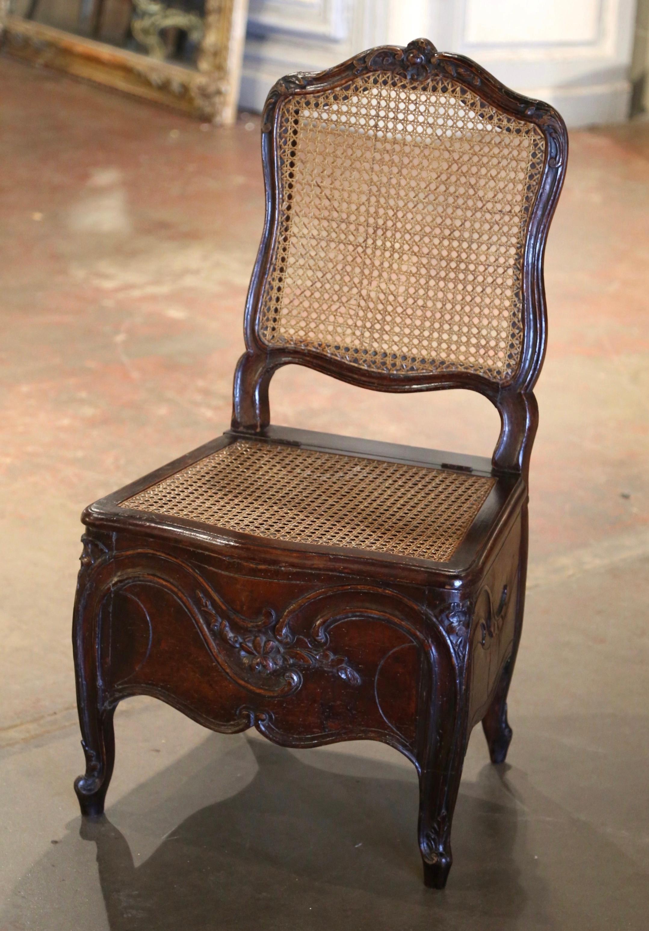 This 18th-century Louis XV chair potty exemplifies the period's intricate craftsmanship and functionality. The chair features an elegantly carved wooden frame with a caned backrest, reflecting the Rococo style's emphasis on curves and natural forms.