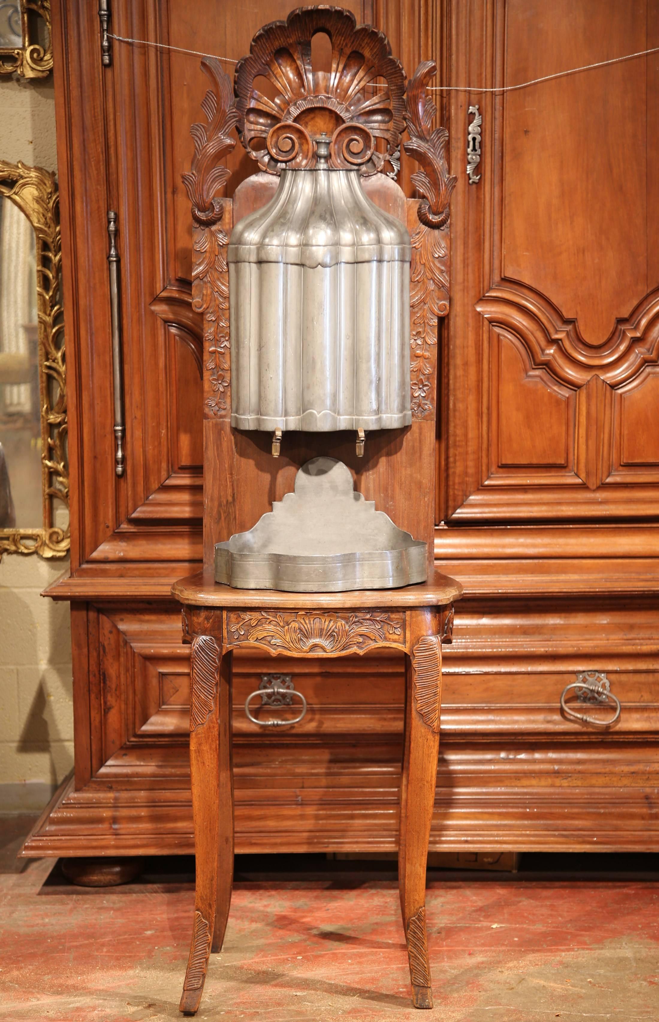 This elegant, antique fountain was crafted in Lyon, France, circa 1780. In the past, this kind of lavabos was actually used for hand washing. This water fountain is made of pewter with bronze faucets, and rests on its original carved fruitwood stand