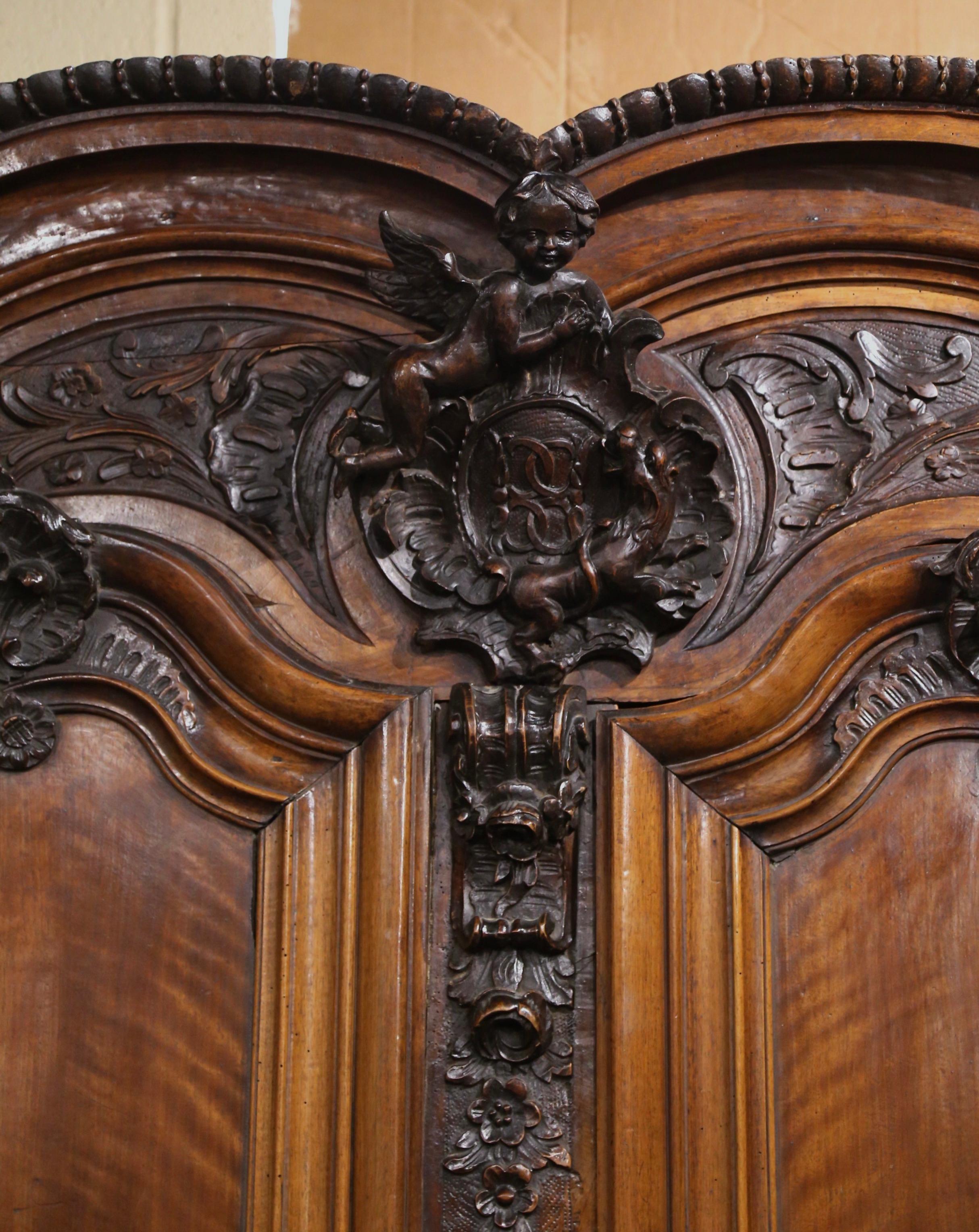 Cette importante armoire lyonnaise a été sculptée à Lyon, en France, vers 1760. Ce grand meuble ancien en bois fruitier repose sur des pieds en chignon au-dessus d'une base droite ; il présente un élégant double chapeau au fronton avec un exquis