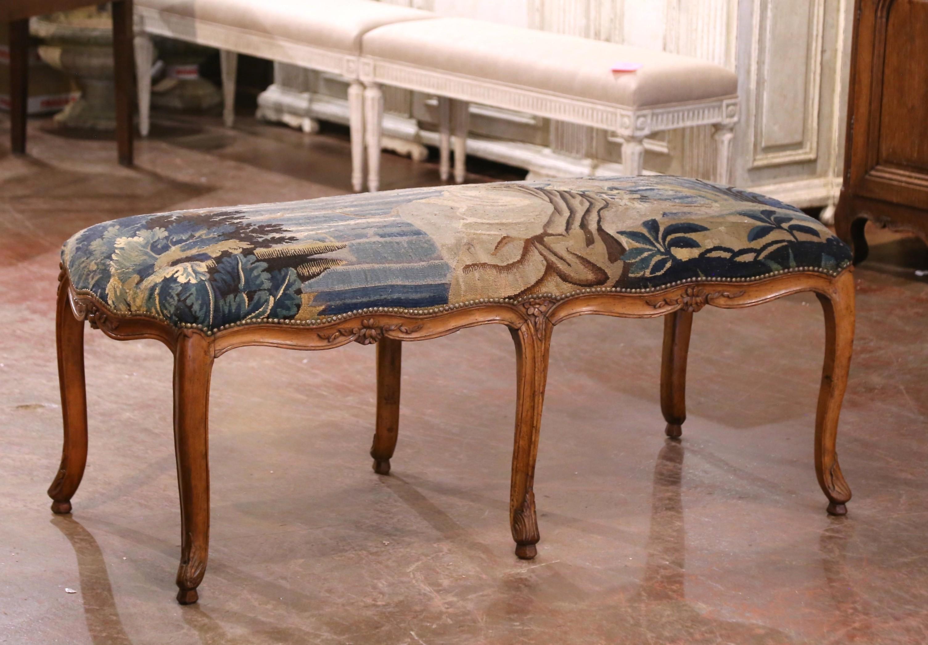 Refined and richly detailed, this 18th century French banquette is a superb example of Louis XV design blended with classical storytelling. Crafted circa 1770, the frame is made of hand-carved walnut, shaped with a gently scalloped apron and resting