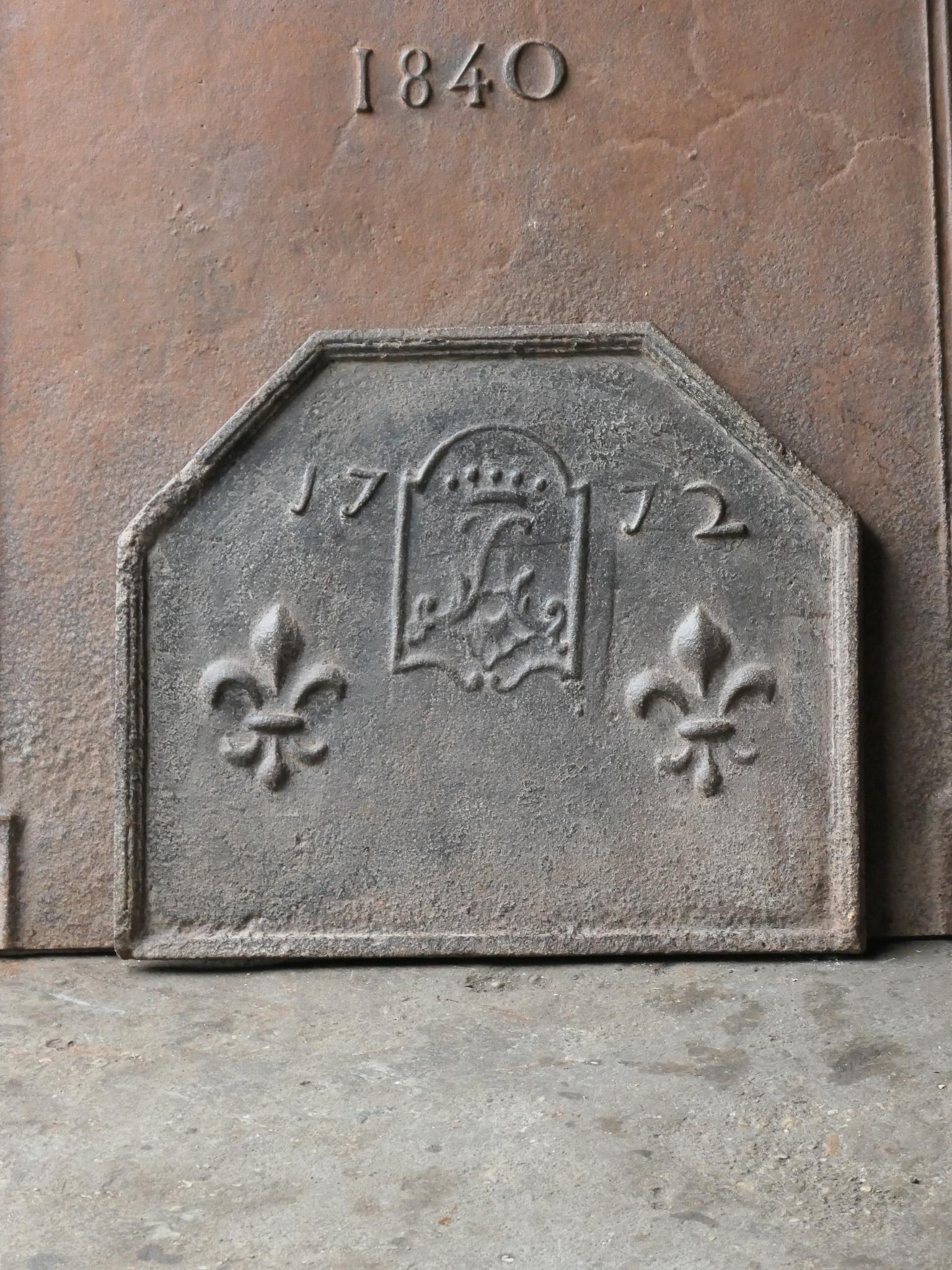 French Louis XV fireback with a coat of arms. On the sides are two fleurs-de-lys portrayed, also known as French Lilies, symbolizing the purity of nobility. The year of production, 1772, is also cast in the fireback.

The fireback is made of cast