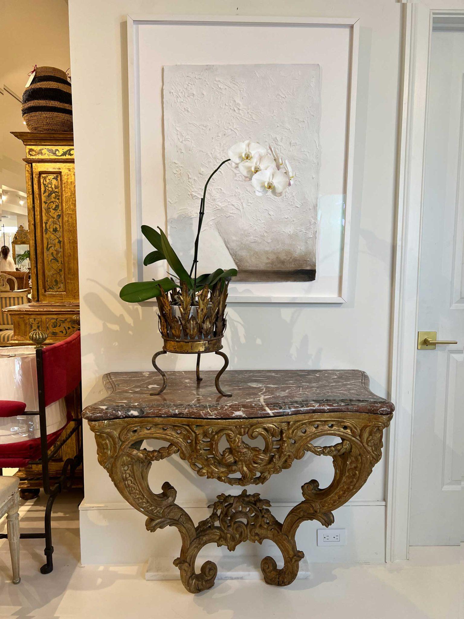 This flamboyant console was clearly designed to be admired. The elaborate carved and gilded base is topped with a conforming marble top with ogee edge. The piece is secured to the wall with brackets allowing the legs to tuck neatly toward the wall.