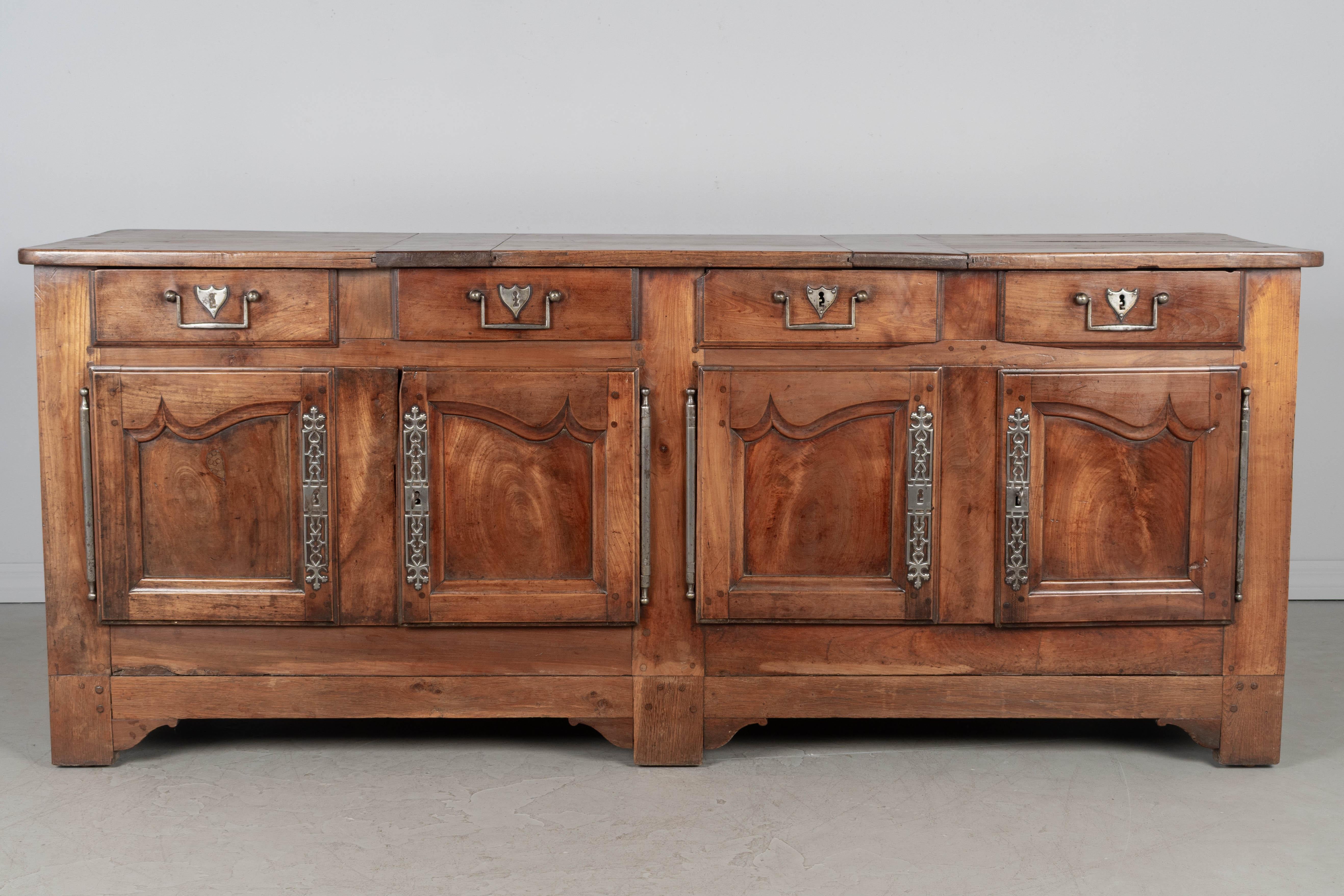 Un'enfilade, o credenza, in stile Luigi XV francese della fine del XVIII secolo, realizzata in ciliegio massiccio, noce e quercia e rifinita su tutti i lati. Quattro cassetti a coda di rondine con tiretti in ghisa sopra quattro ante a pannelli