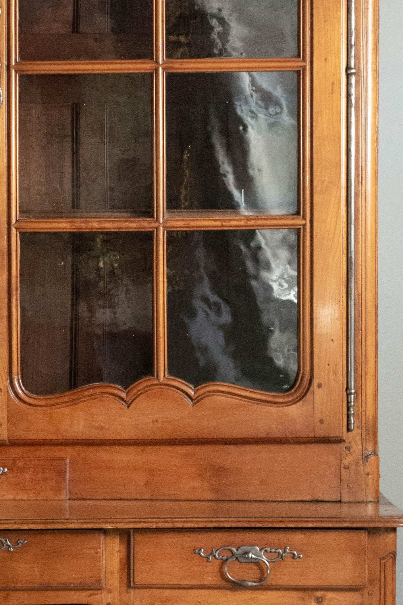 A grand scale 18th century French Louis XV Period bibliothe`que, or bookcase, from the Loire Valley. Made of solid cherry wood with chestnut as a secondary wood and constructed in two parts. The large bookcase has the original hand-blown glass paned