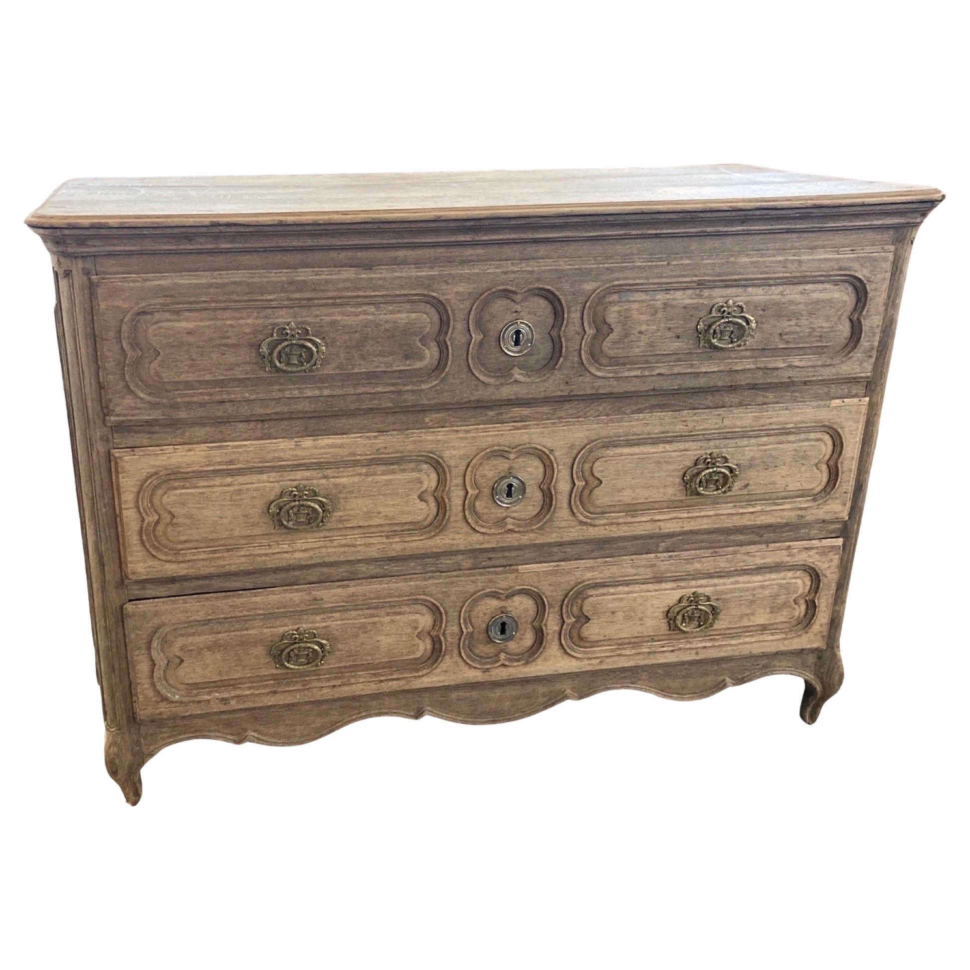 Louis XV commode hand-made in France in the mid 1700s using oak and pegged construction. The chest shows the typical overall look of the Louis XV style, with cabriole feet, scalloped apron and carved overlay drawers. The top is made of three boards