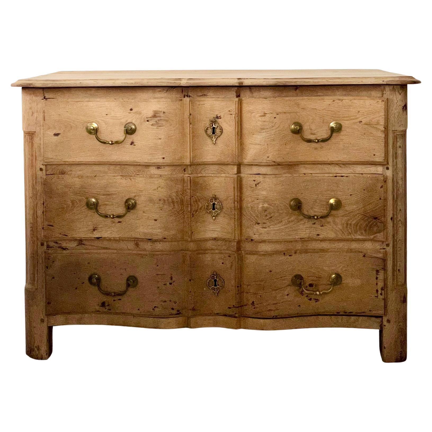 18th Century French Louis XV Period Commode en Arbelete in bleached oak finish. The front facade having an arbalete with shaped top. The original bronze hardware drop handles and escutcheons adorn the fronts of each drawer. The corners are rounded