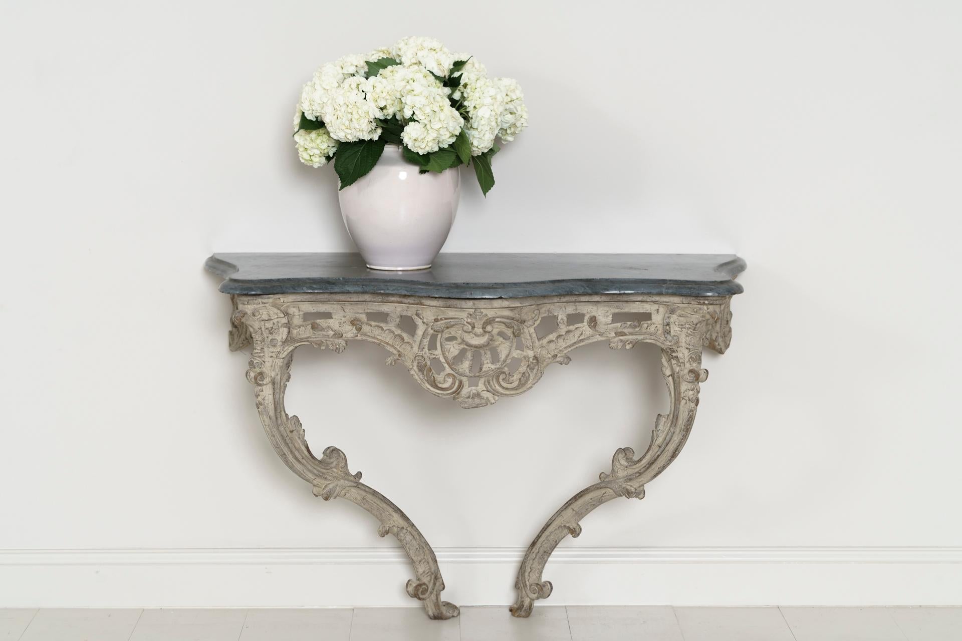 A large 18th century French console table from the Louis XV period in original paint. The original blue turquin marble top is bevelled and contoured to complement the base. The frieze is scroll-carved and pierced.