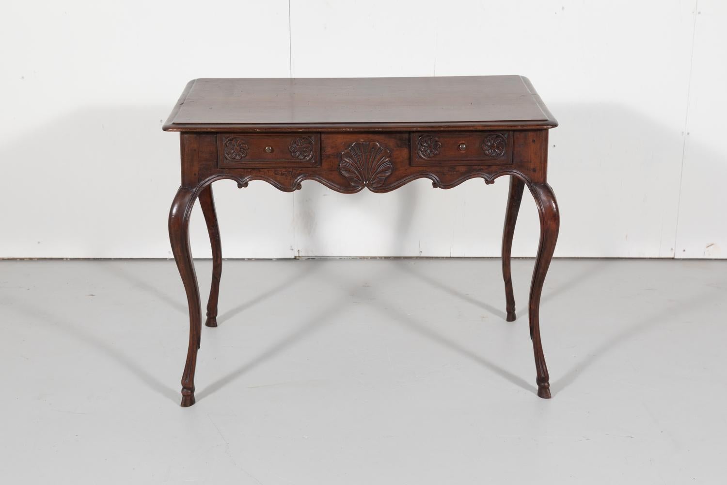 Fine 18th century French Louis XV period side table or ladies desk handcrafted in solid French walnut by talented artisans near Lyon. This richly carved French table features a rectangular top with moulded edges and rounded corners sitting above an