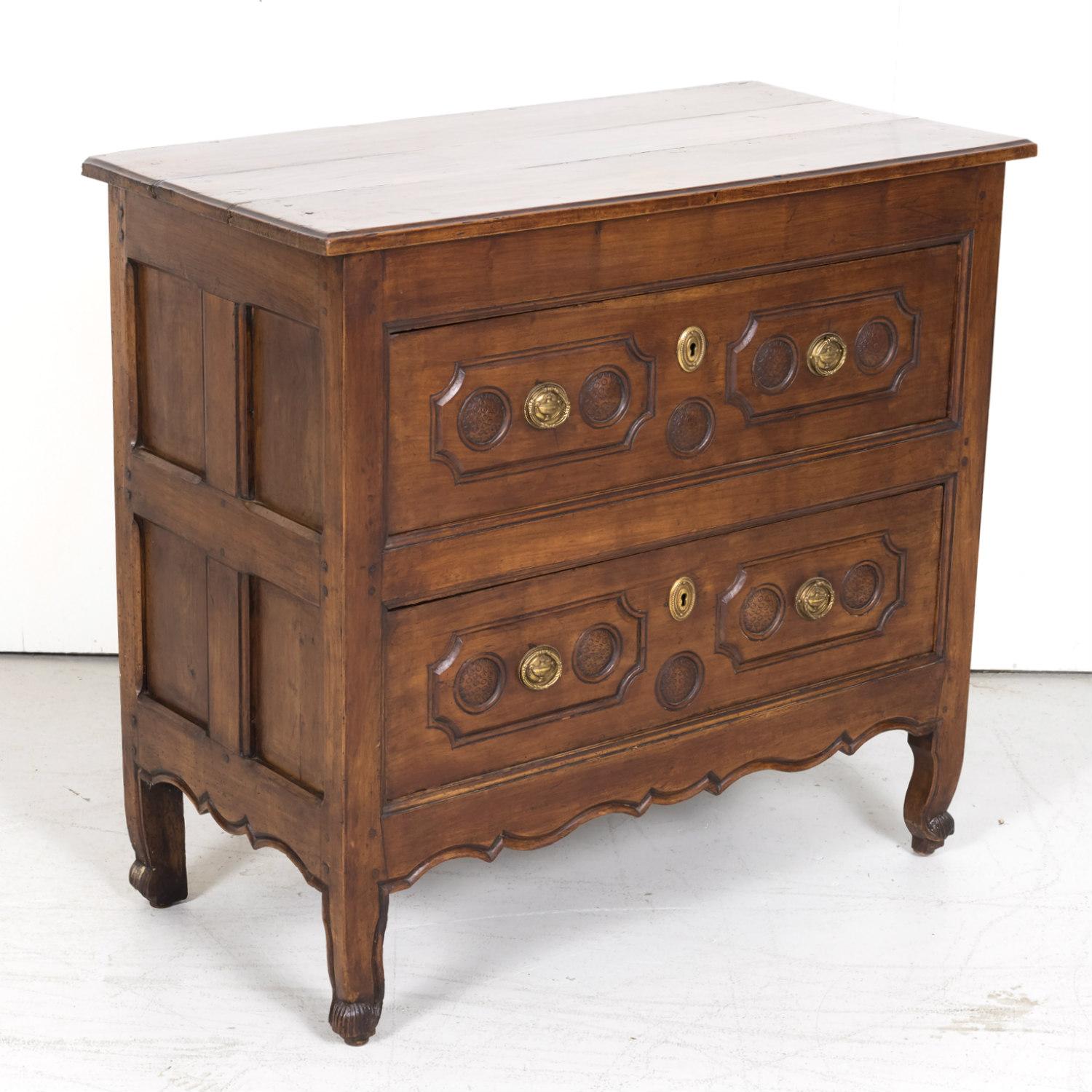 An exceptional 18th century French Louis XV period solid cherry provincial commode handcrafted by master artisans near Lyon, circa 1740s, having a rectangular plank top above two full length drawers with shaped raised panel moldings featuring