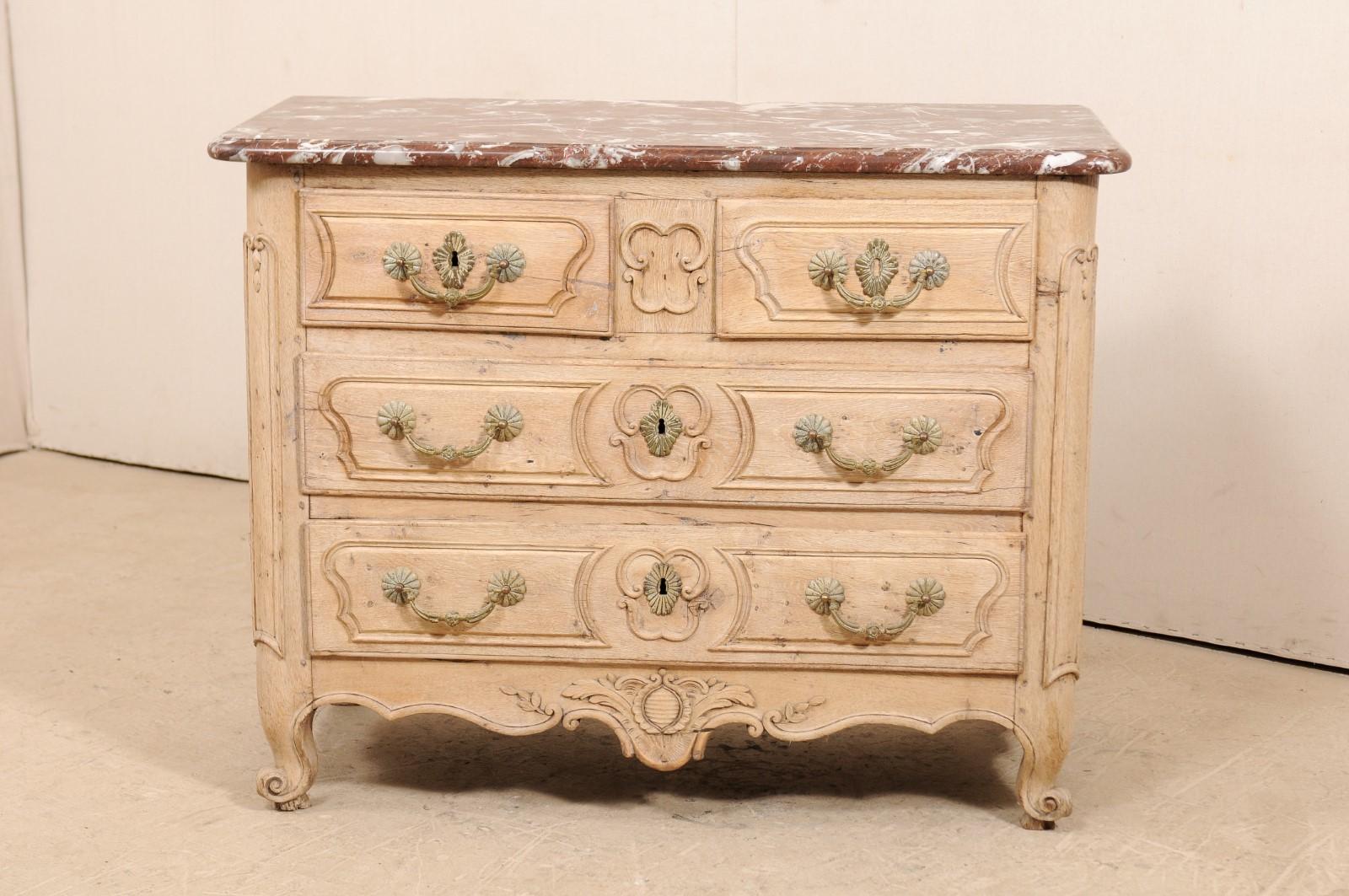 A French period 18th century finely carved, marble top commode. This French period Louis XV Provincial commode, circa 1750-1760, features two smaller drawers at top, divided with plaque at center, over two full length drawers, each drawer has