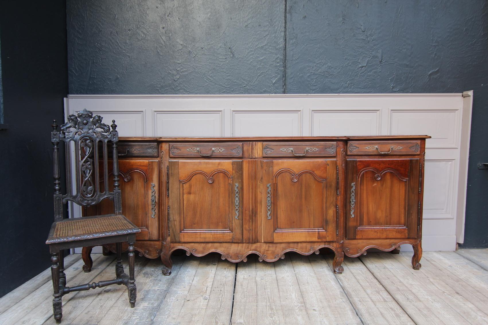 Exquisite French Louis XV baroque sideboard from the Dijon region circa 1740. Made of walnut and oak. 
Standing on 8 feet with 4 nicely carved scrolled cabriole legs between a beautiful cut and carved base on the front. 
There is a double door on