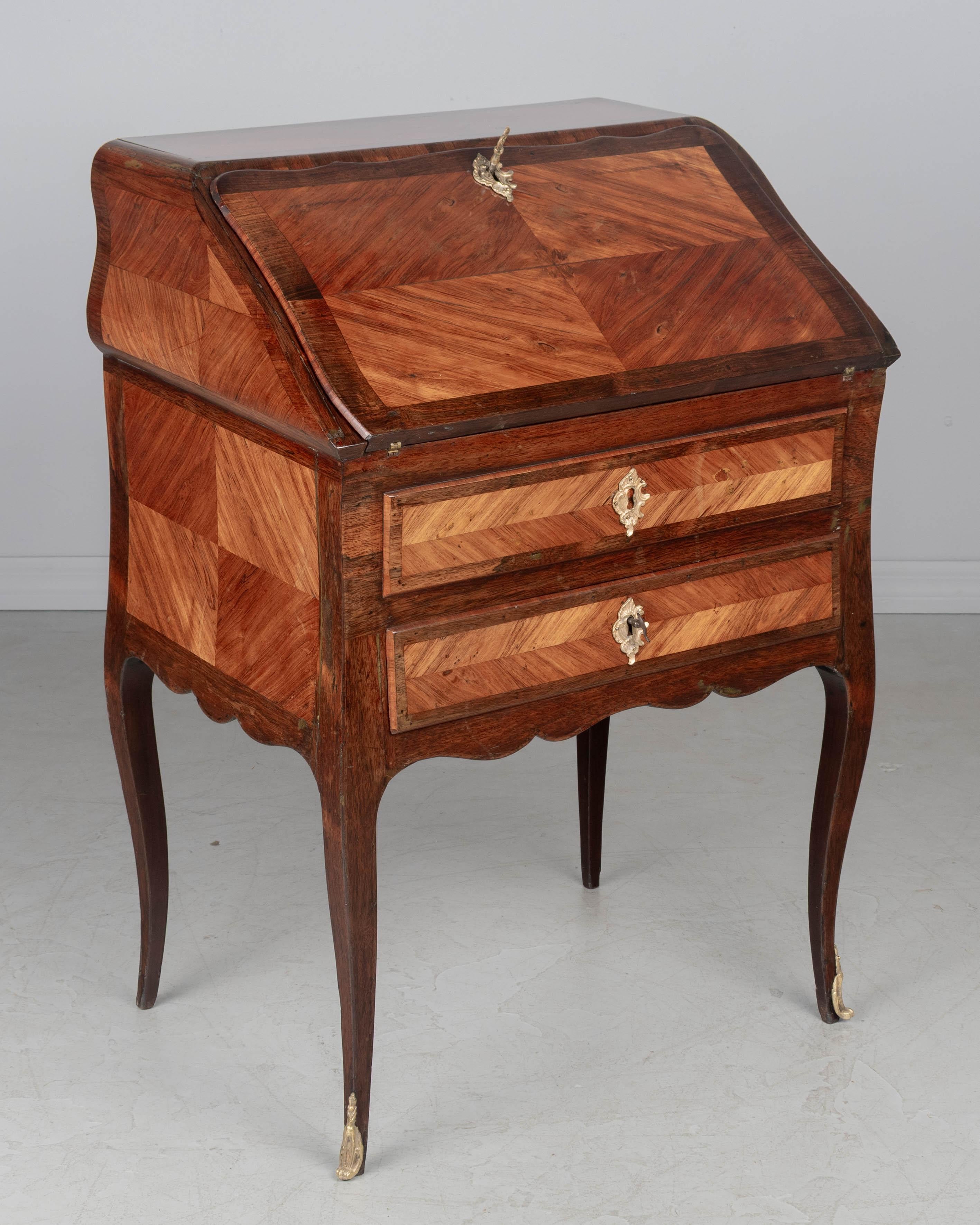 Un bureau de pente francese del XVIII secolo, realizzato con impiallacciature di mogano, palissandro e tulipier e quercia come legno secondario. Il fronte inclinato si apre su una superficie di scrittura in pelle e un interno foderato in palissandro