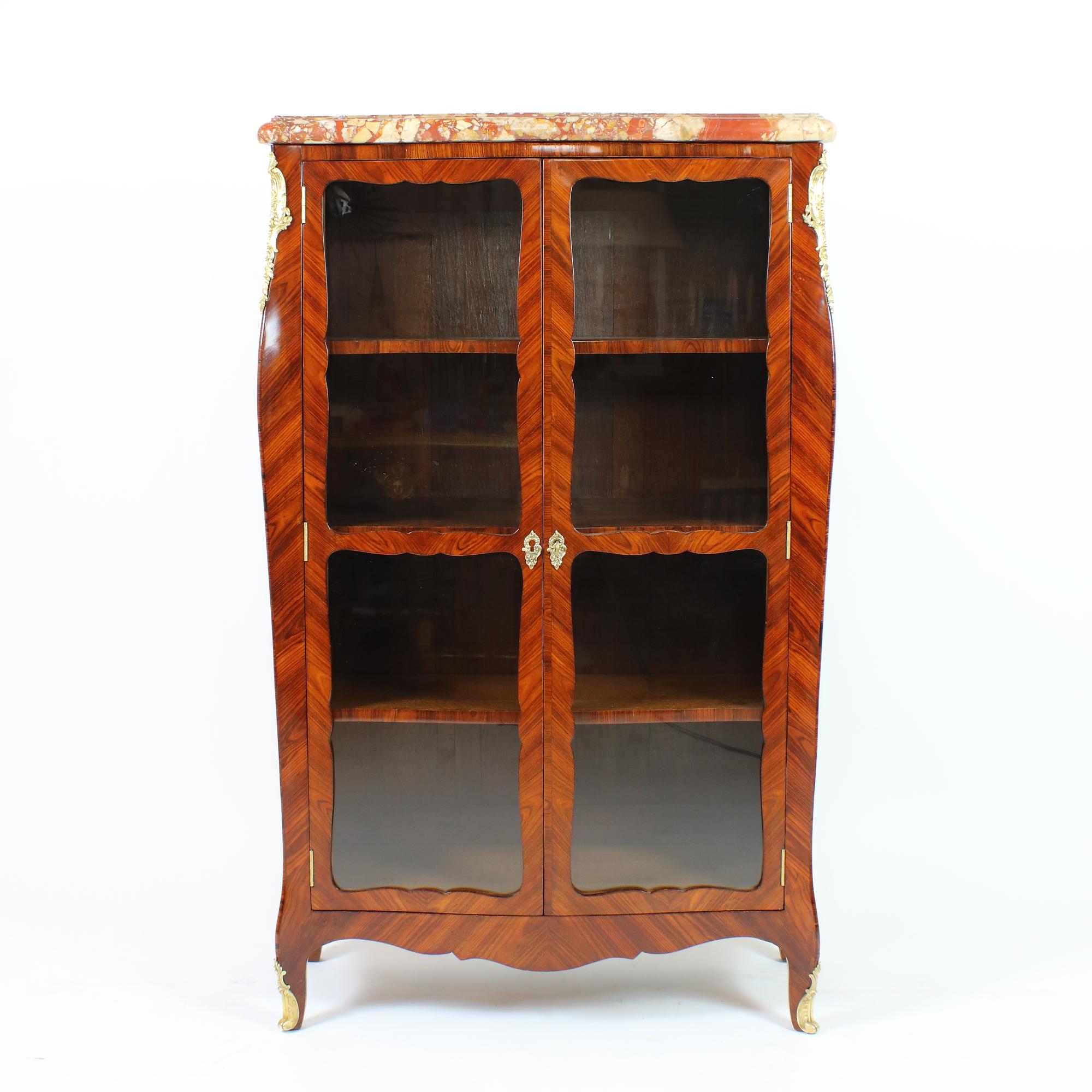 18th century French Louis XV small Marquetry bookcase or Vitrine

Rectangular vitrine or bookcase standing on four cabriole feet, front and sides slightly curved, the angles pointedly extended. Mirrored marquetry on three sides. Two full-height