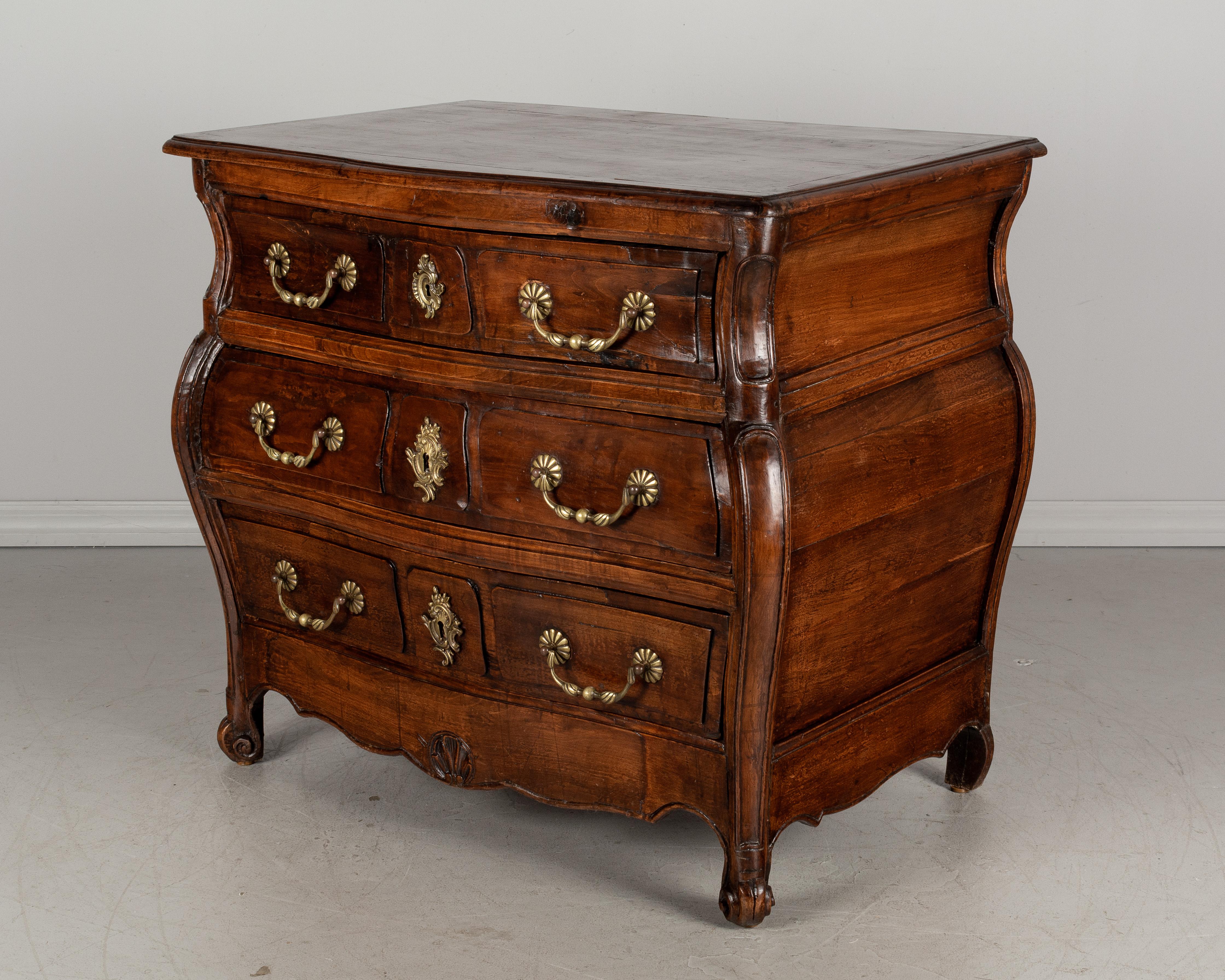 An 18th century French Louis XV style commode, or chest of drawers, from the Bordeaux region made of solid cherry wood. Small in scale with nice proportions and bombé form. Three dovetailed drawers with fabric lining. Original bronze hardware.