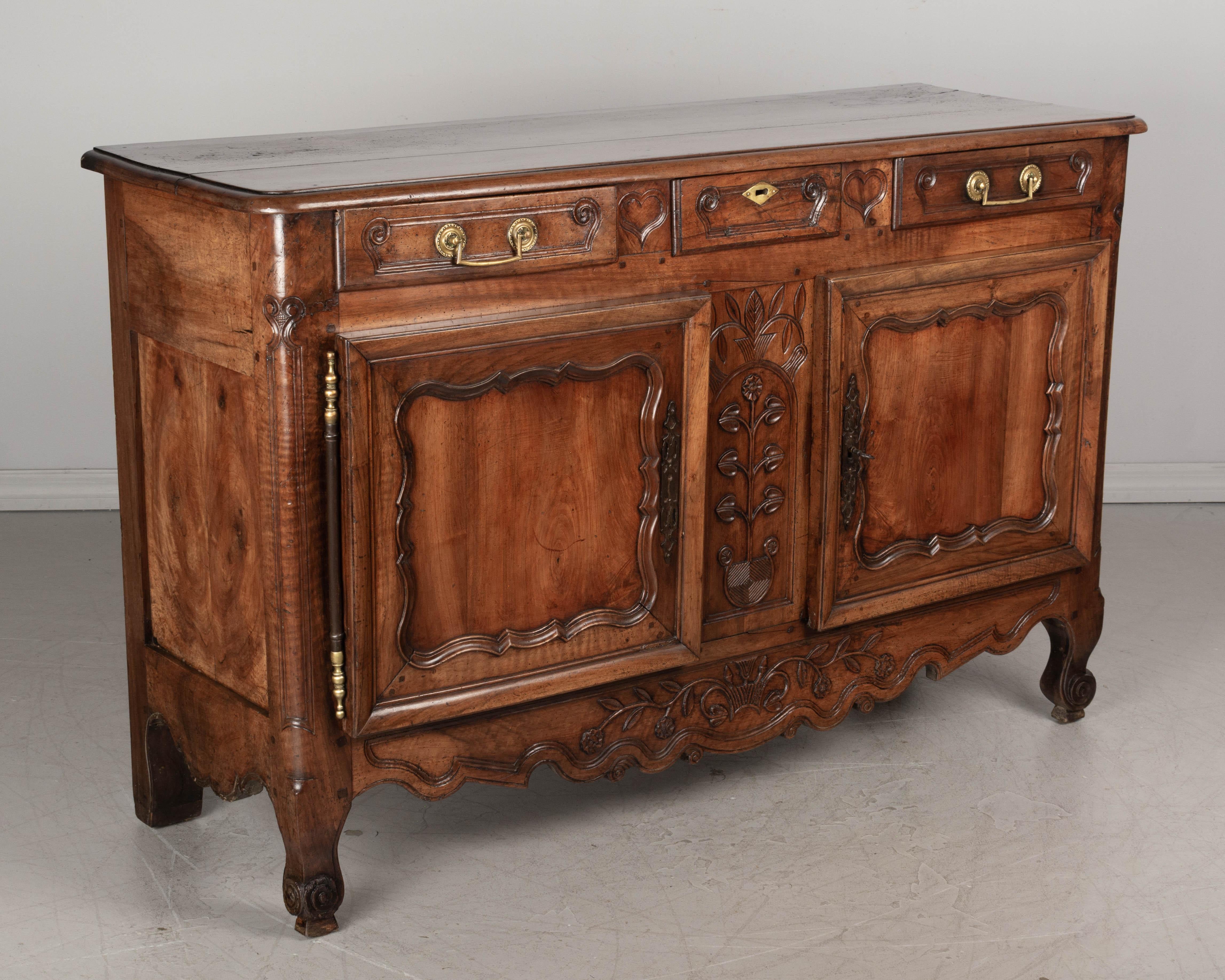 A fine 18th century Louis XV style French Provincial bridal buffet made of solid walnut, likely from the Burgundy region. Three dovetailed drawers with original cast brass pulls. Two paneled doors with thick, beveled frames, newer lock and key,