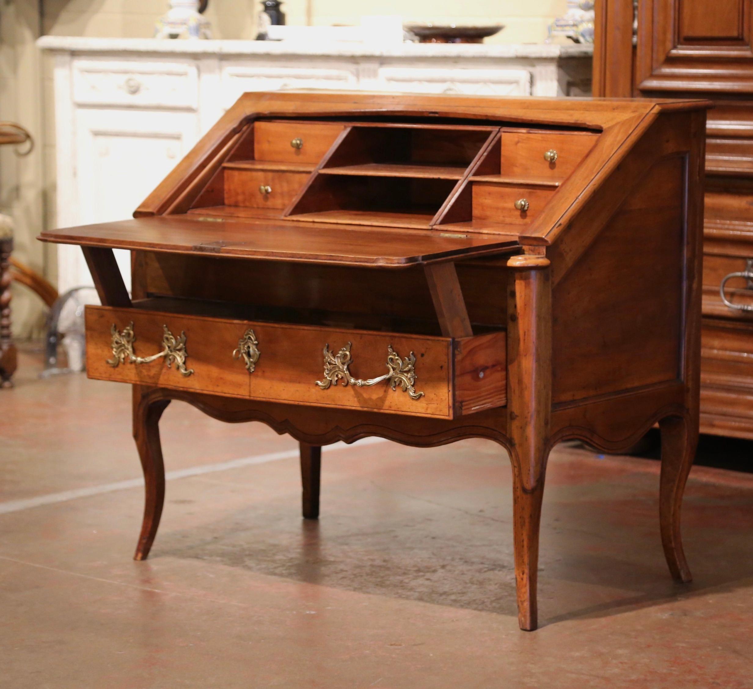 Carved in southern France, circa 1760, the fold out secretary is both stylish and functional; the elegant writing desk crafted from solid walnut, stands on cabriole legs over a scalloped apron and dressed with bombe drawer across the front