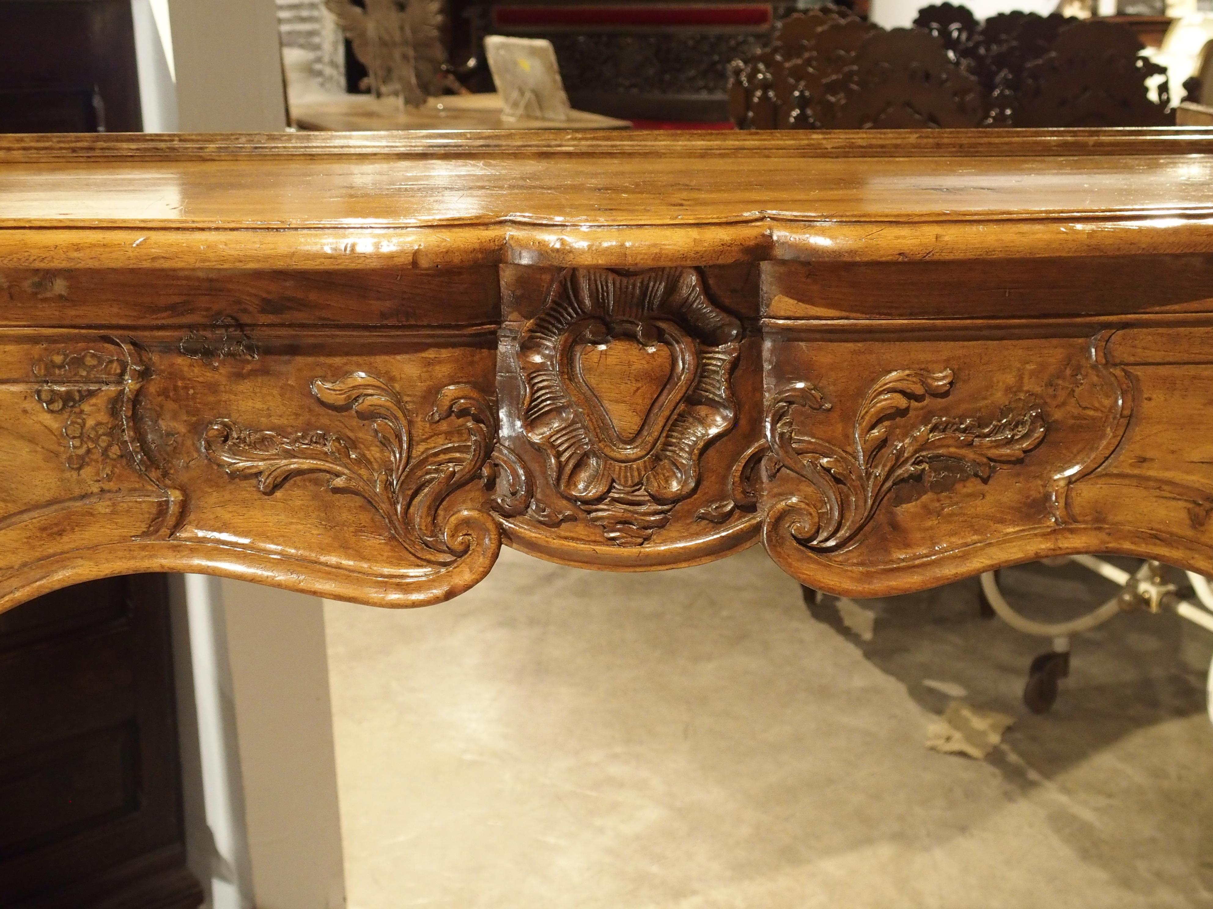 This period Louis XV walnut wood mantel dates to the middle of the 18th century. The shaped front Silhouette is in the crossbow shape, or known in France an “arbalete”. The top is over a conforming body and has an overhang of an inch on all sides,