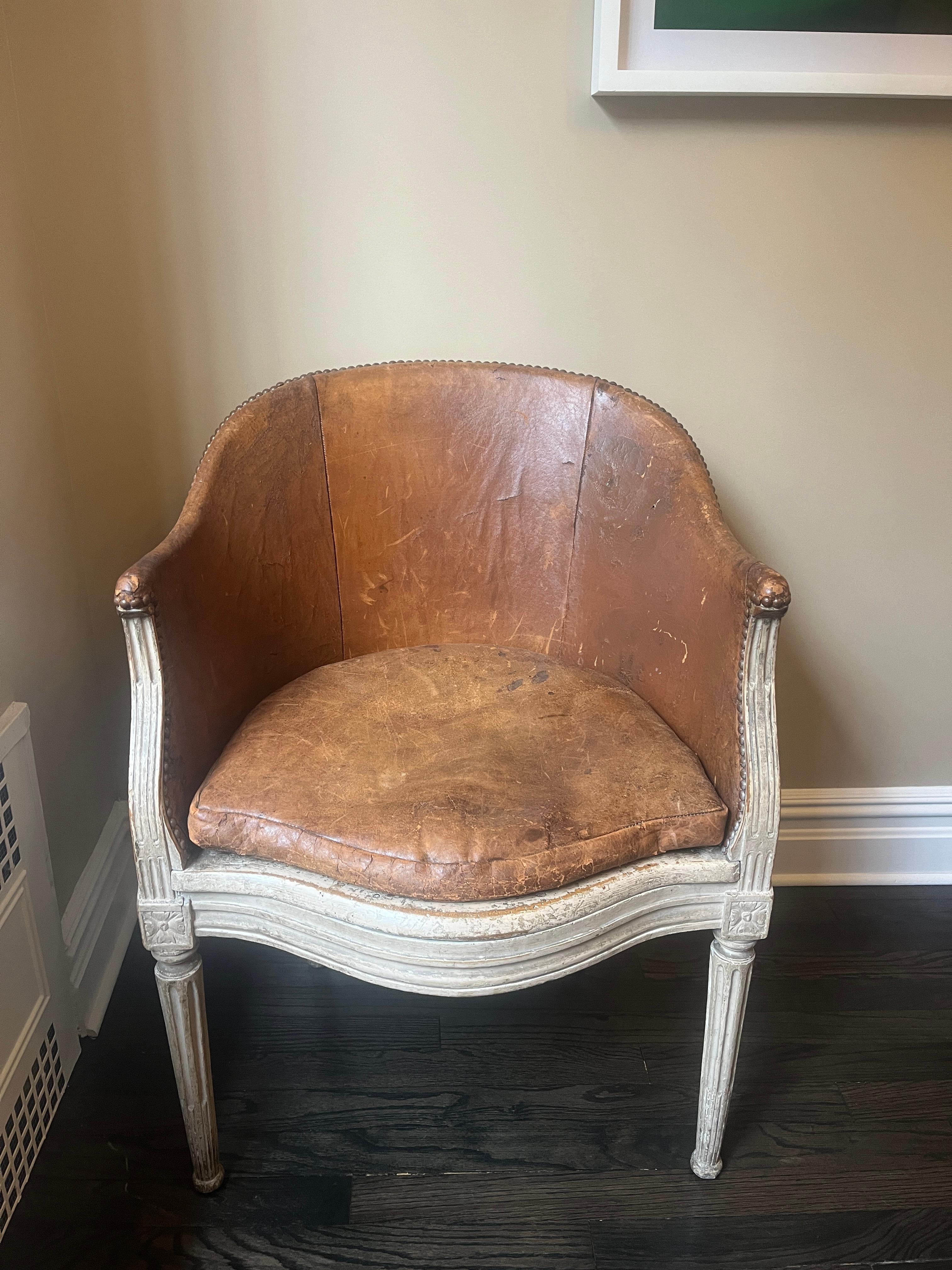 18th Century French Louis XVI Bergère chair, with brown leather seat and back. Painted wood frame, carved fluted tapered legs, brass nail head detail, and cane backing in good condition.  


Addl. dimensions: 27