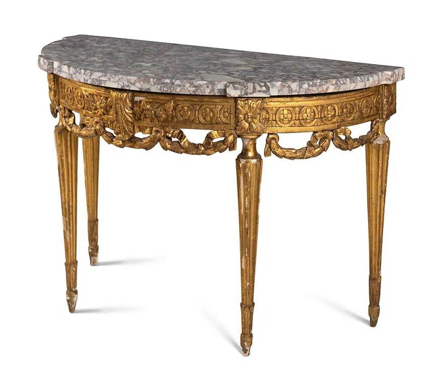 The 18th Century French Carved Demi Lune Console with Marble Top is a luxurious and elegant piece of home furniture inspired by the Louis XVI style. The console features intricate carvings on its wooden frame, with a marble top adding a touch of