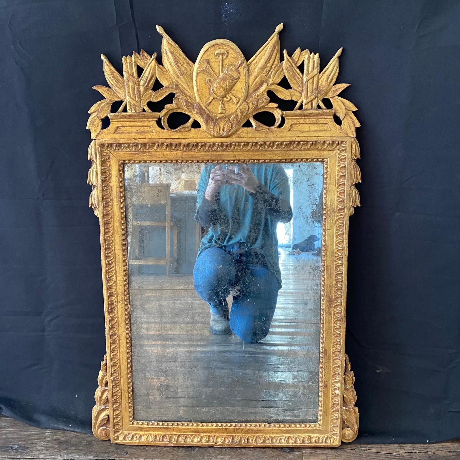 Miroir de mariage en bois doré de style provençal français Louis XVI du XVIIIe siècle. Magnifique cimier tridimensionnel sculpté avec des feuilles d'acanthe et des drapeaux, et une plaque ovale avec une corne.  et un carquois de flèches. Des