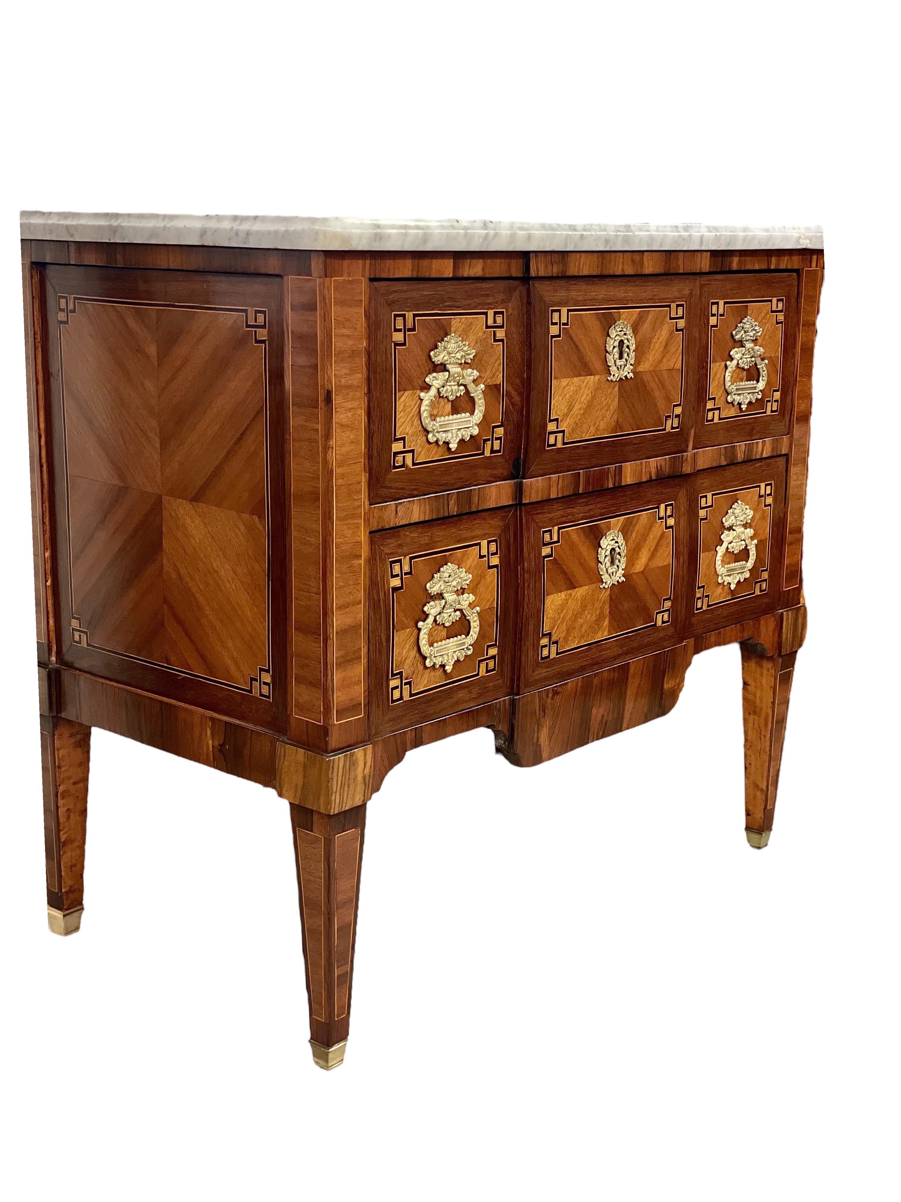 An exceptionally beautiful marquetry inlaid commode 'à Ressaut' opening with two wide drawers, and crafted in the Louis XVI style. 
This very decorative late 18th century chest of drawers features a central projection at the front, and rests on four