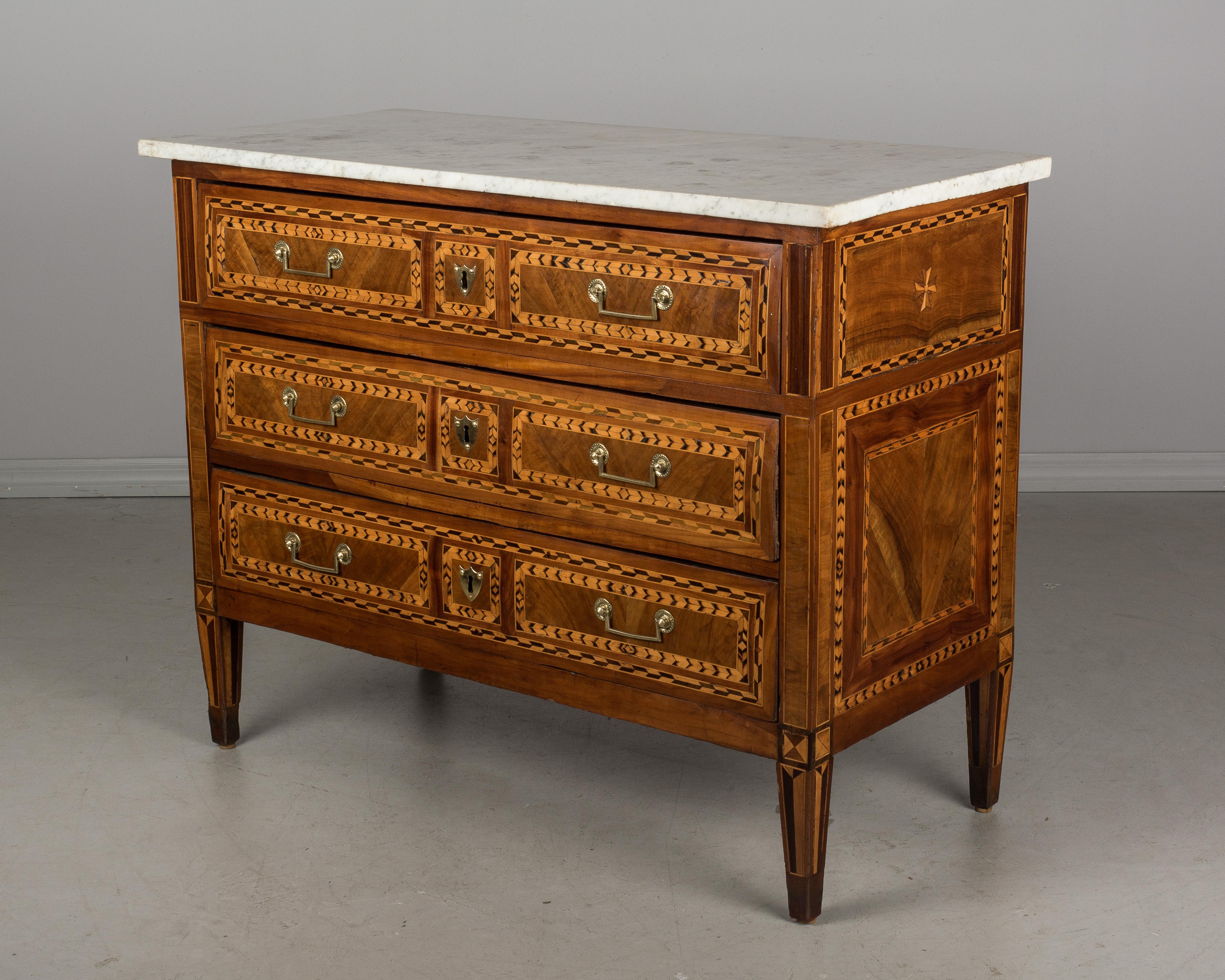 An 18th century Louis XVI marquetry commode from the East of France, beautifully crafted with various wood veneer inlay. French polish finish. Three dovetailed drawers with original brass hardware. Locks are present, there is no key. Original white