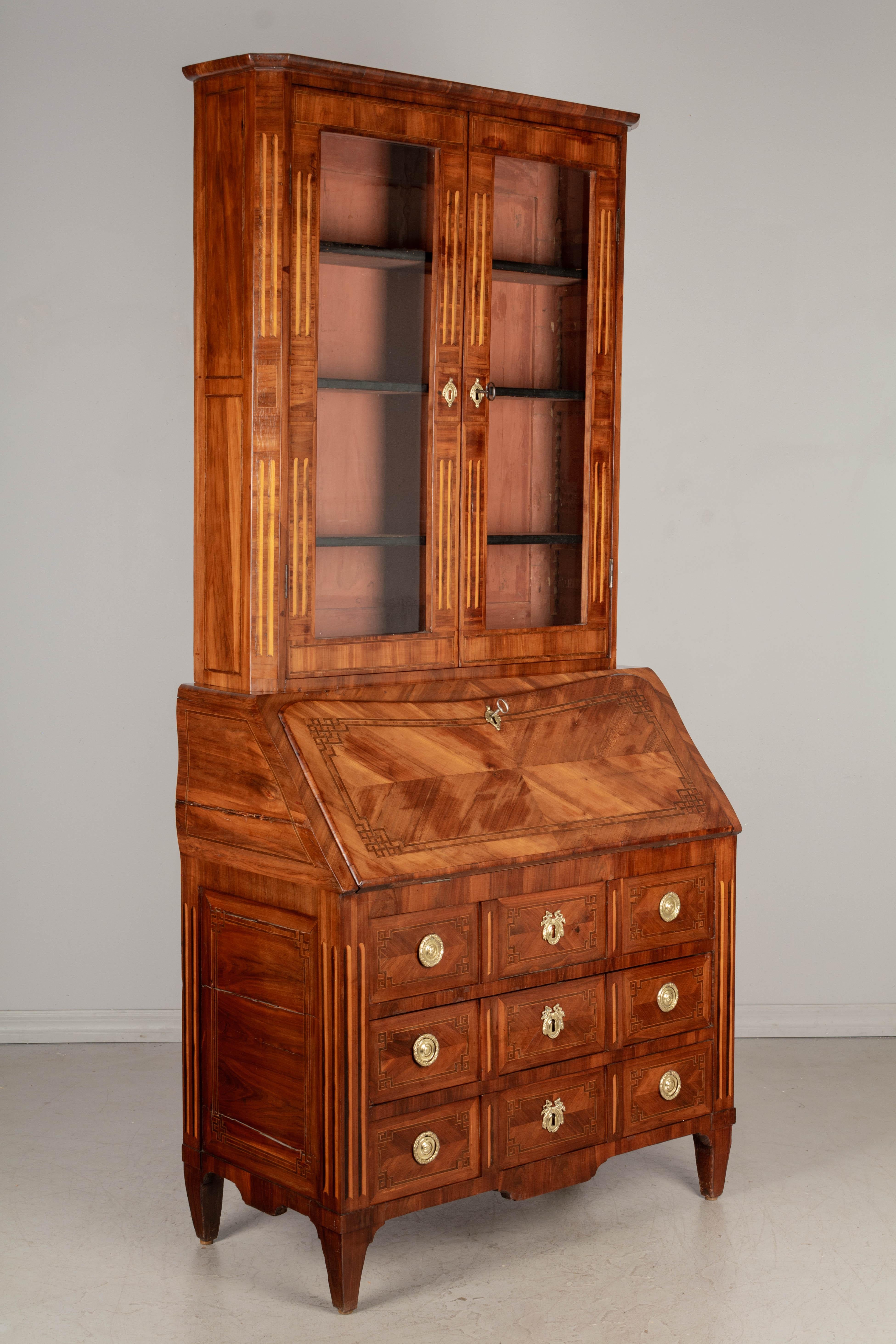 An 18th century French Louis XVI marquetry secretaire, or secretary desk with bookcase. Beautifully made with book matched veneer of mahogany and fine inlay of walnut and mahogany. In two parts, the top bookcase has the original glass paned doors
