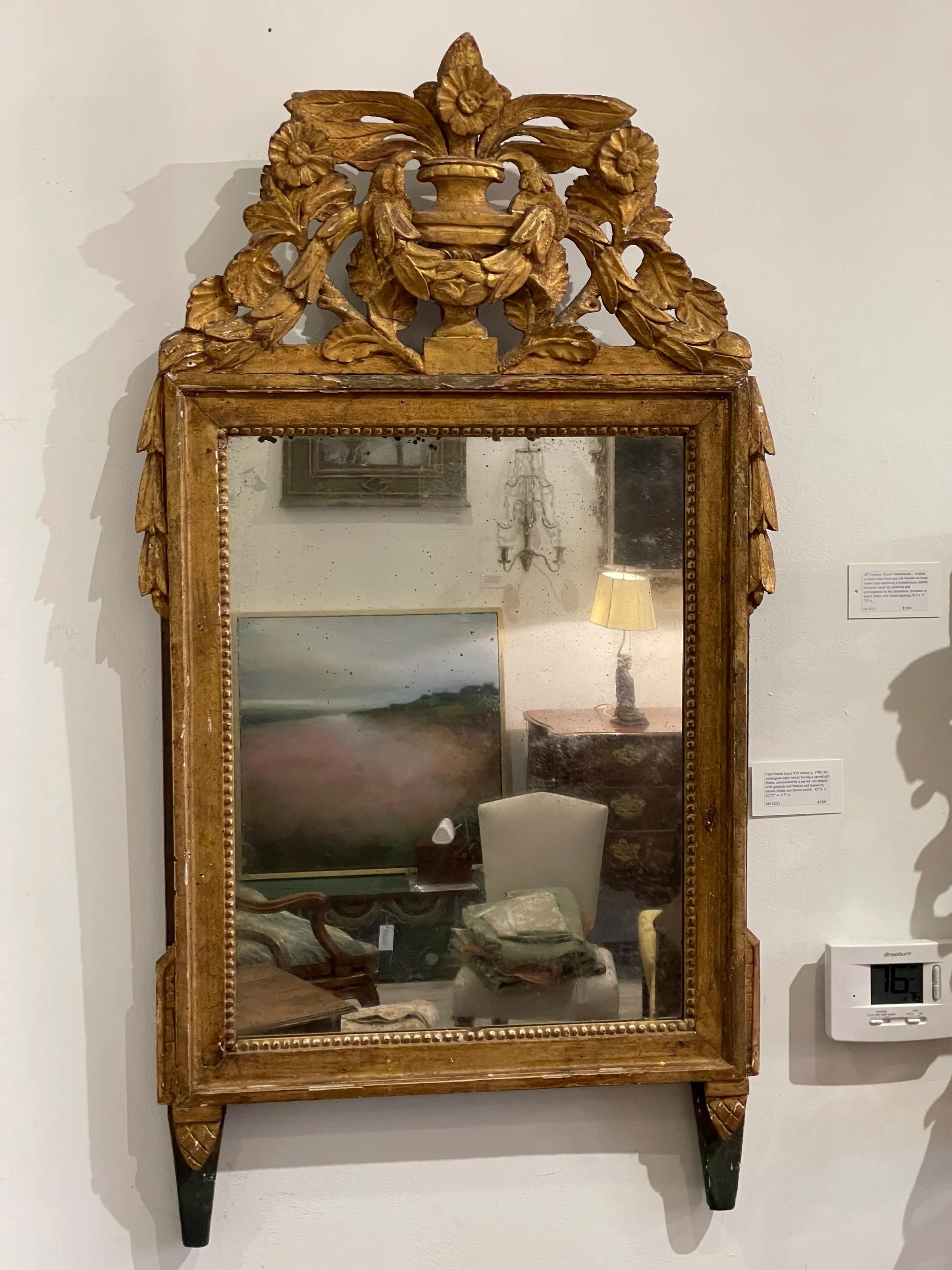 Fine French Louis XVI mirror, c. 1780, the rectangular early mirror having a carved gilt frame, surmounted by a carved urn draped with garlands and flanked and topped by carved foliate and flower motifs. Measures: 42” H x 22.75” W x 3” D.

