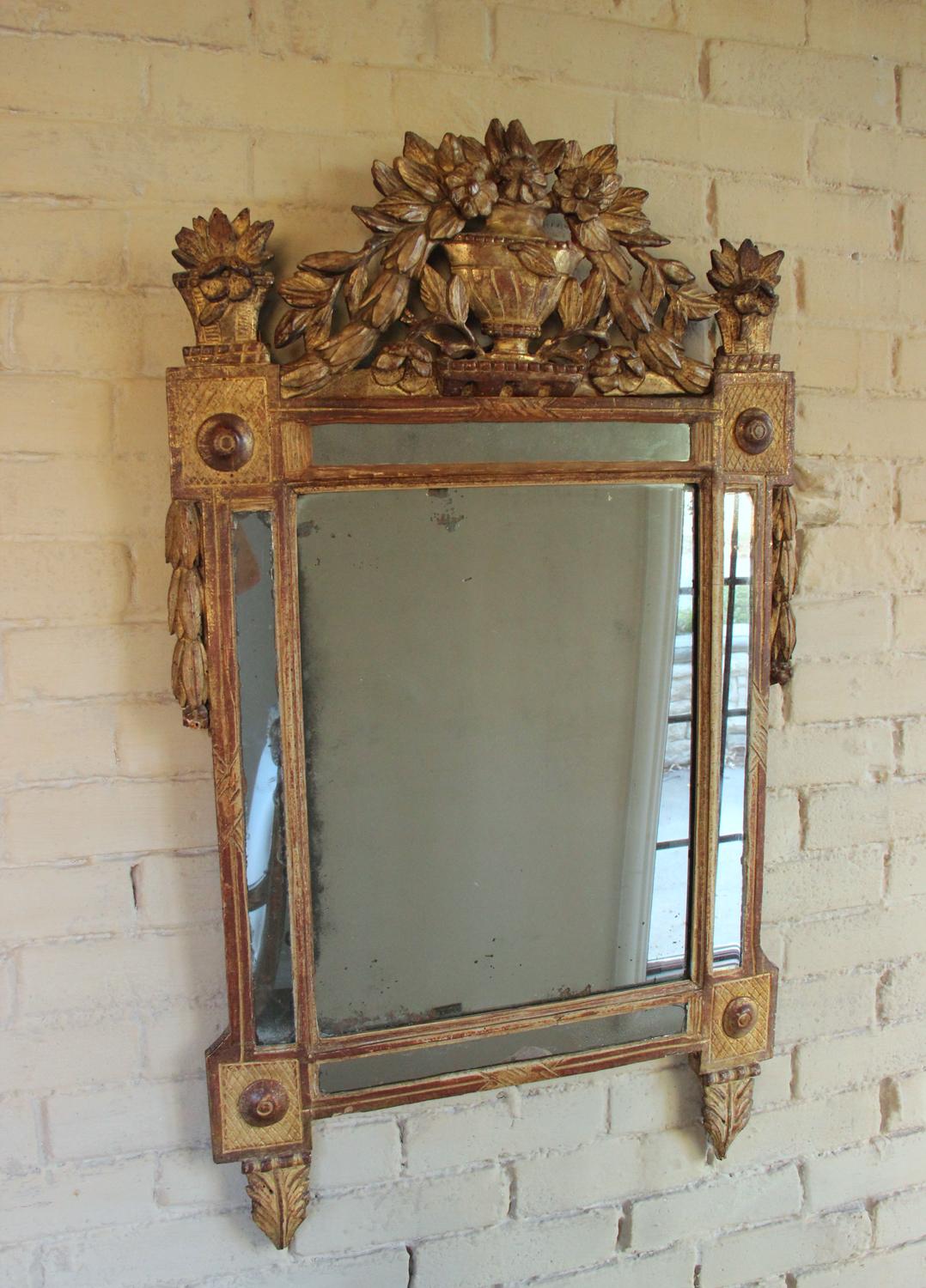 A beautifully carved French original giltwood mirror from the Louis XVI, 'Louis Seize', period with urn pediment and floral motif. Original mercury mirror plate. The carved crest features an urn filled with a bouquet of trailing flowers. The floral