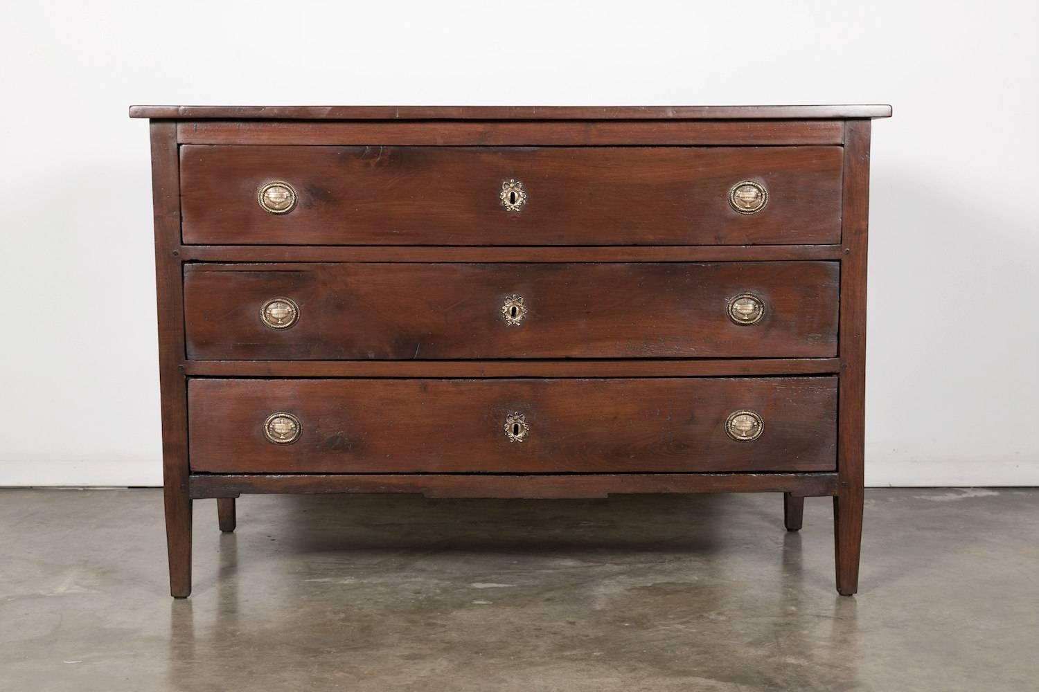 A fine 18th century period Louis XVI commode handcrafted in solid walnut by skilled artisans near Lyon, having three drawers adorned with original bronze hardware. Raised on tapered legs. The beauty is in the refinement of the details of this chest.