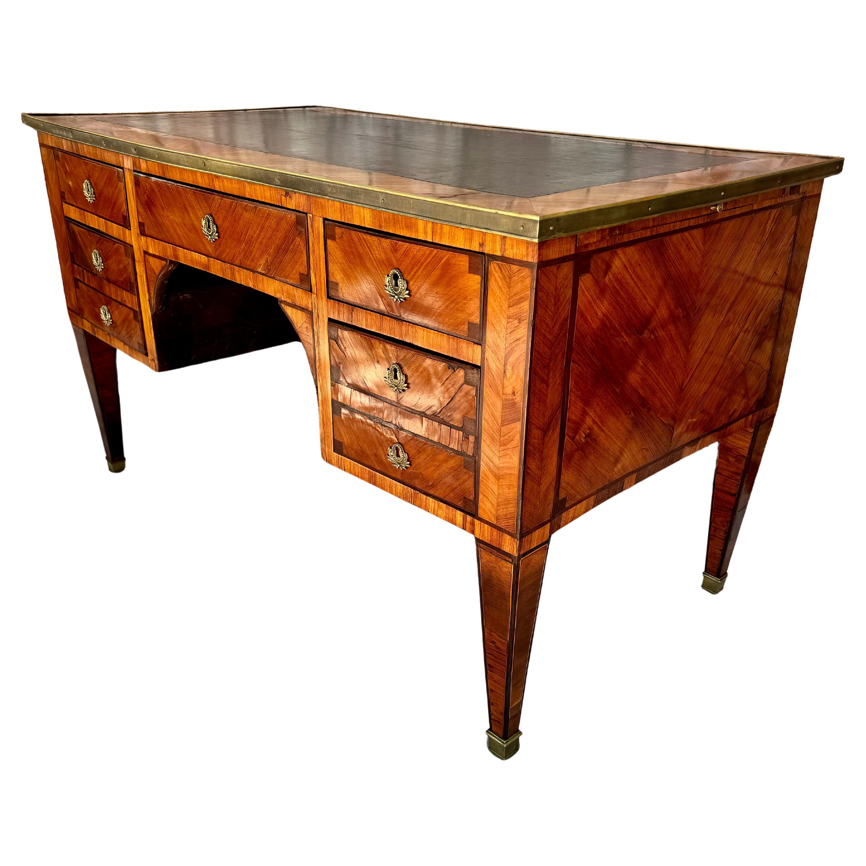 Handsome late 18th Century French Louis XVI style writing desk with leather insert on top. Desk features a middle drawer, with three drawers on left and three drawers on right side. Brass hardware and tapered legs. Desk has completely finished front