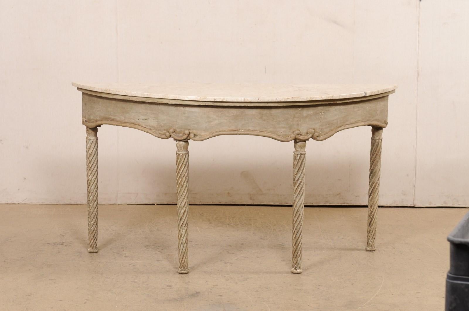 A French carved wood and marble top console table from the 18th century. This antique table from France has a lovely oblong demi shape to it; with marble top that rests upon an apron with a softly swagged skirt, and presented upon four rounded legs
