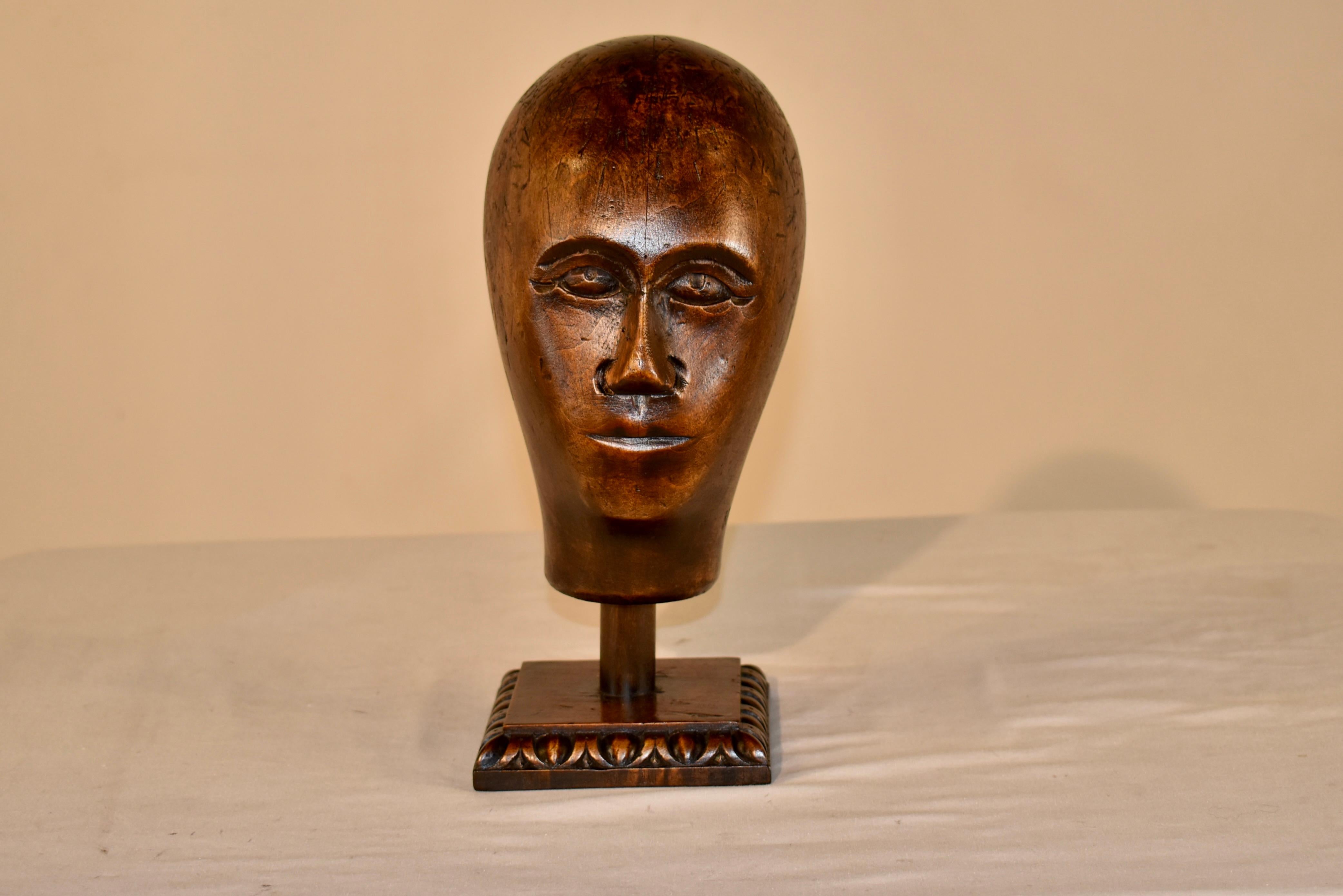 Testa di modista in noce intagliata a mano del XVIII secolo, proveniente dalla Francia.  Le caratteristiche sono finemente intagliate in stile arte popolare e il pezzo è sostenuto da una base vintage in Oak.  Anche la base è stata intagliata a mano
