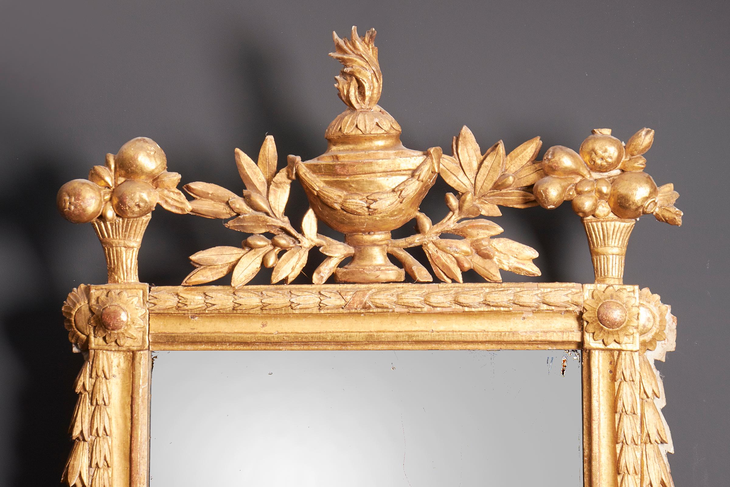 Specchio da parete neoclassico in legno dorato intagliato, Francia, fine del XVIII secolo, circa 1770-1790, fregio elaborato e intagliato, gli angoli con un girasole, lo stemma con un'urna e delle volute, il piatto è un ricambio storico.