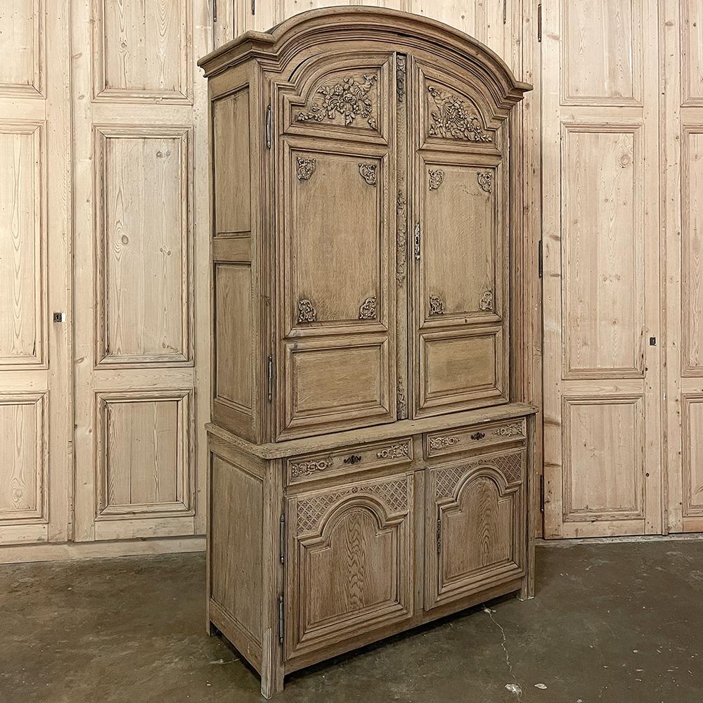 18th century French neoclassical buffet a Deux corps in stripped oak is a majestic example of fine French craftsmanship, featuring a boldly arched chapeau de gendarme cornice atop the upper tier of doors which are divided into three distinct paneled