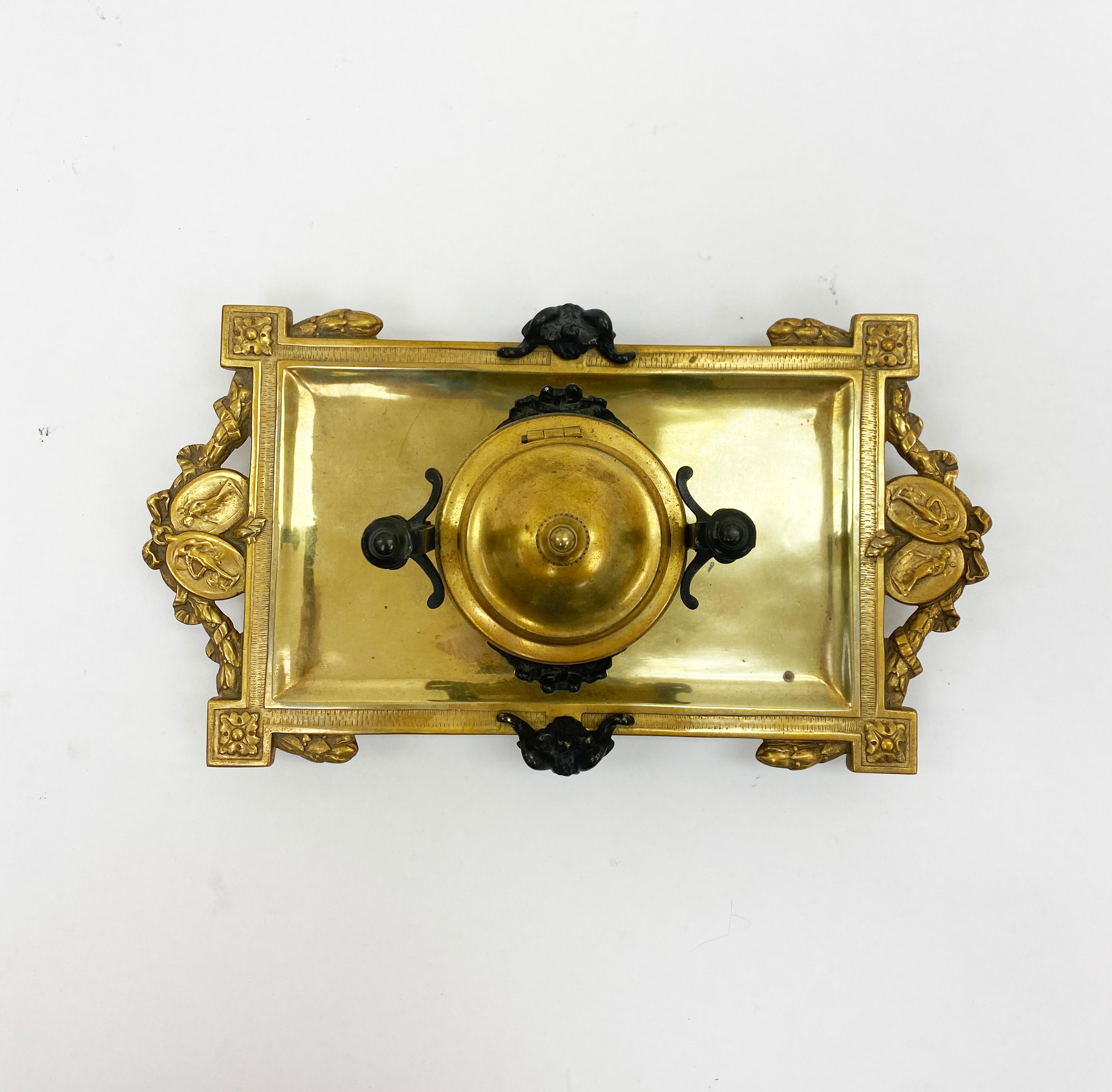 Bronze inkwell, circa 1790. Rectangular form with gilt bronze footed base with patinated dark bronze handles and mounts. Item has singular pot in the center of the tray. The floral designs and color scheme enhance the neoclassical style.