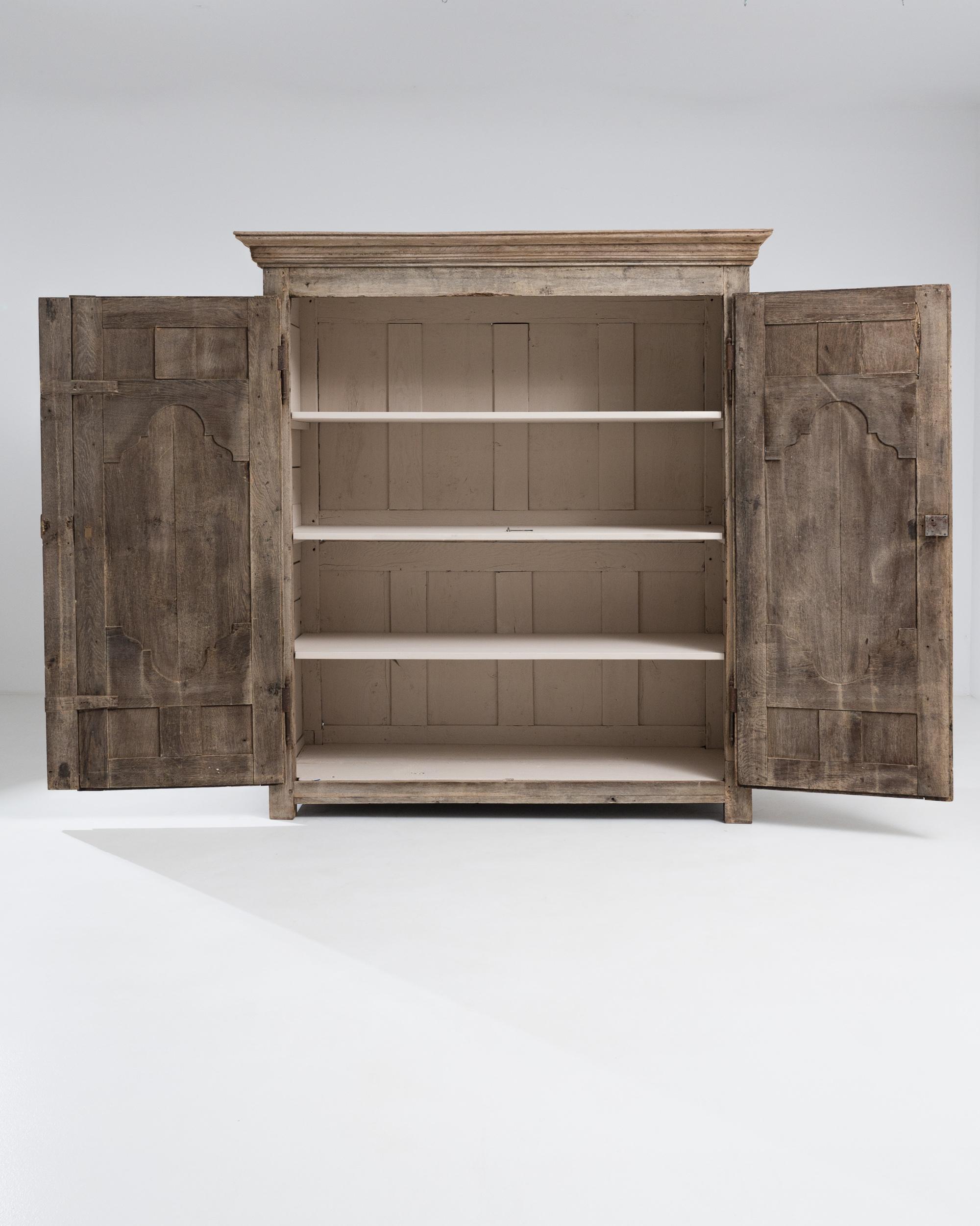 This provincial oak cabinet combines antique grandeur with a simple country charm. Built in France in the 1700s, the warm, sunny tone of the restored oak lends a youthful freshness to the antique frame; the cream-painted shelves of the interior have