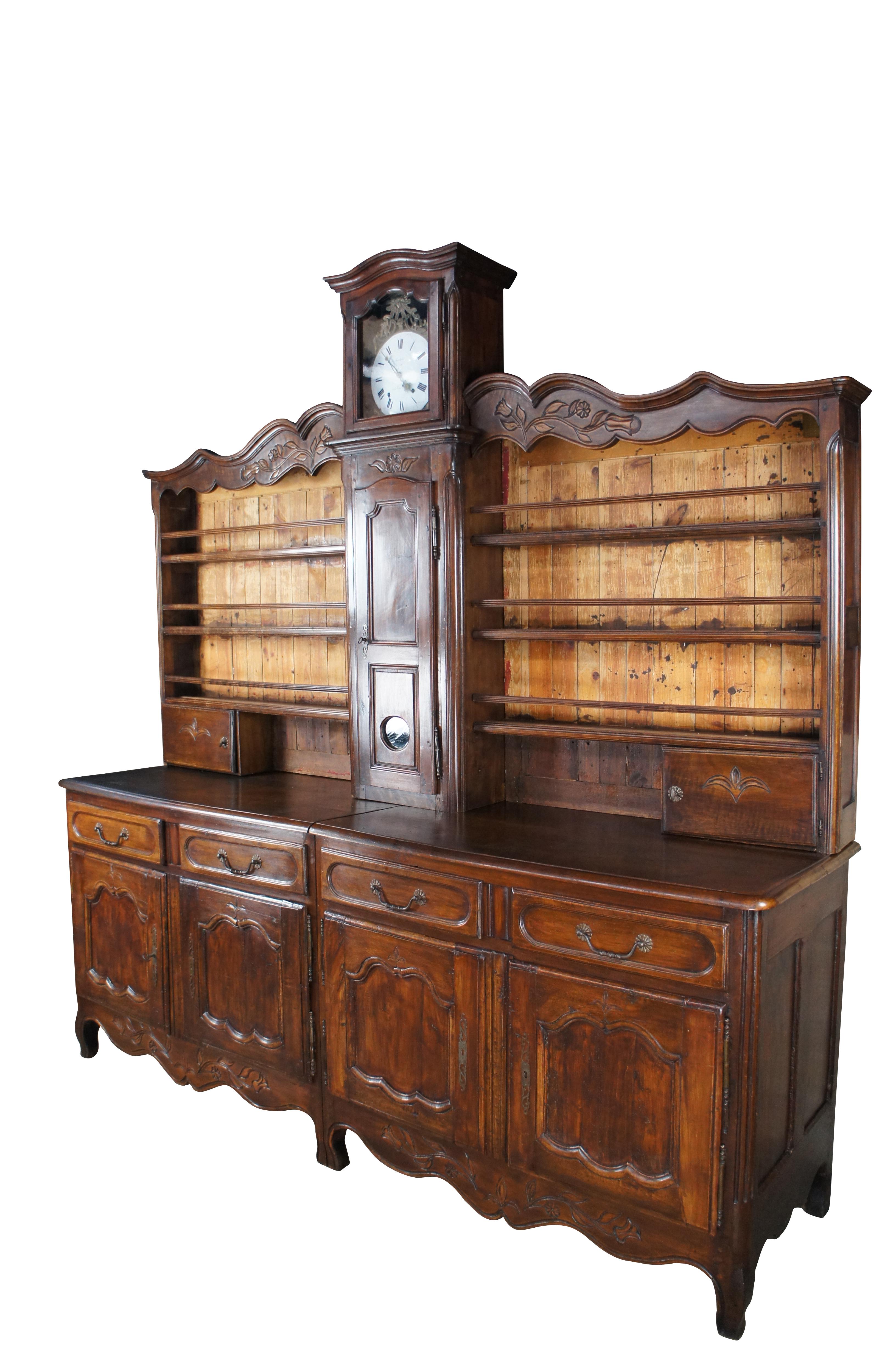 #41402

Antique late 18th century Country French buffet / hutch / vaisselier with Horloge (clock).  Made of oak featuring French country / provincial styling with carved flowers / florals and fleur de list accents.  A serpentine China plate rack