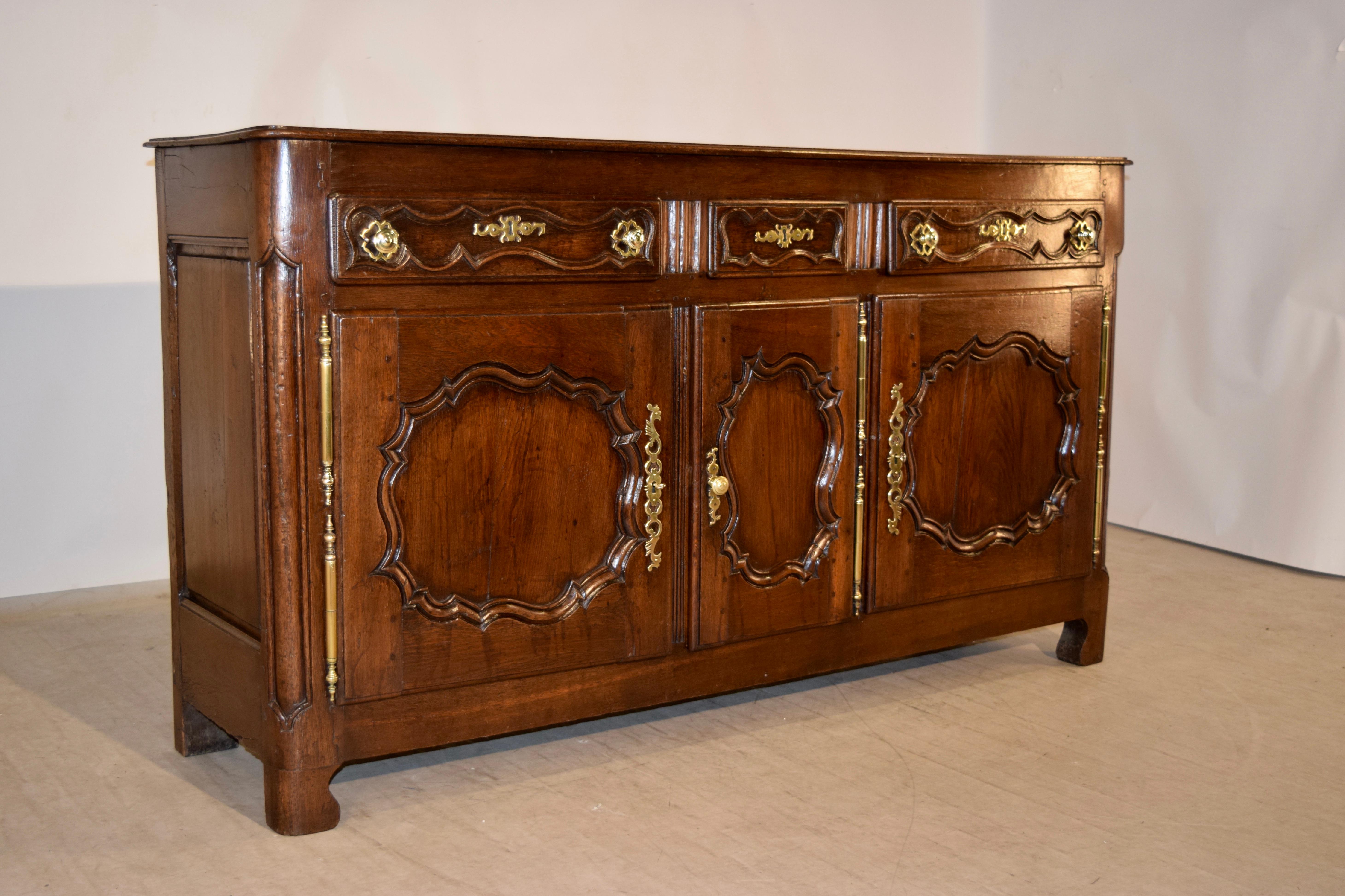 18th century oak enfilade from France. The top is made of planks and has rounded and beveled edges, following down to an elegant case with simple lines. There are three drawers over three doors, all with hand-carved elegantly scalloped panels. The