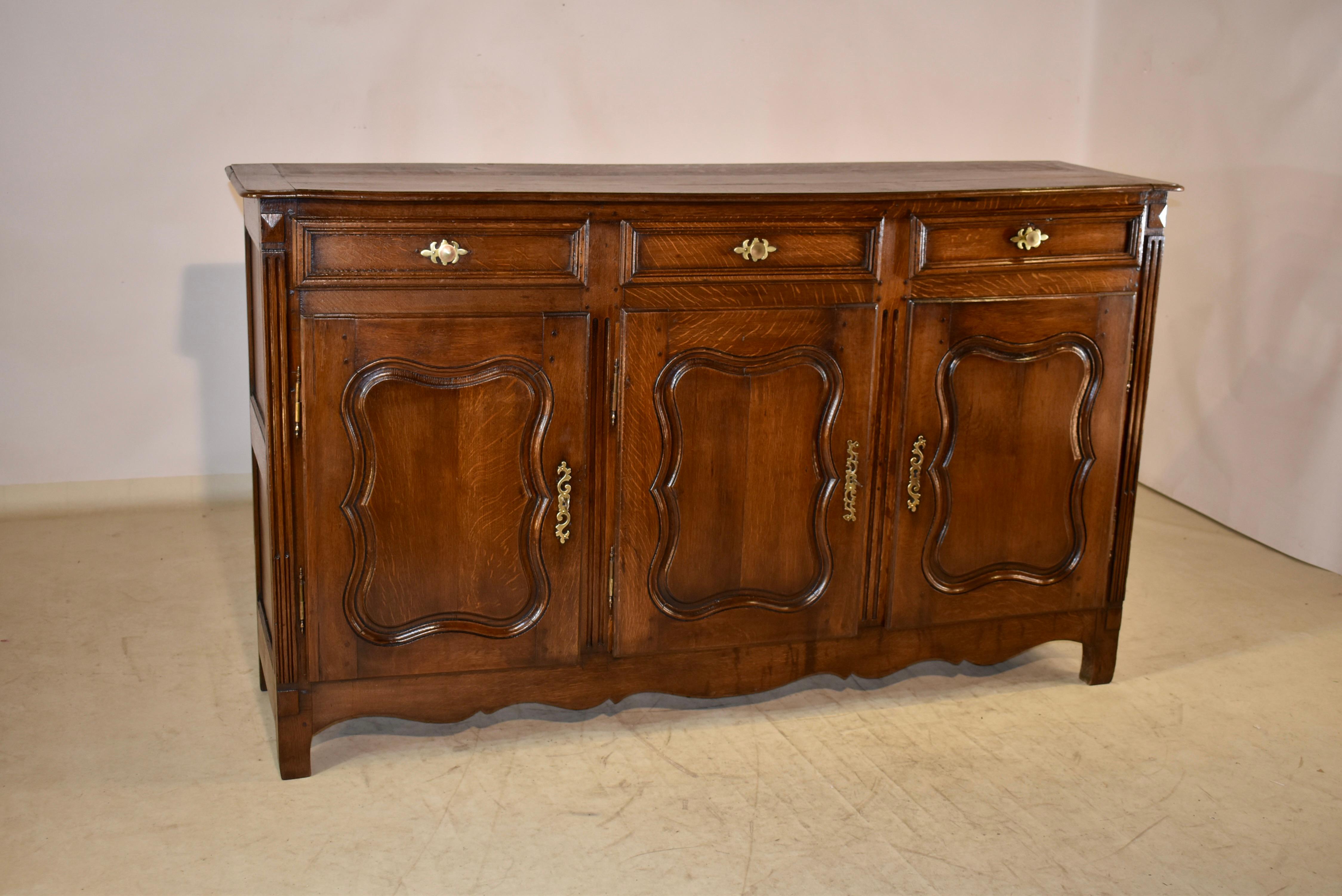 18th century oak enfilade from France with banded ends and beveled edges around the top. The sides are paneled and the front contains three paneled drawers over three raised paneled doors, which open to reveal storage. There is a scalloped skirt