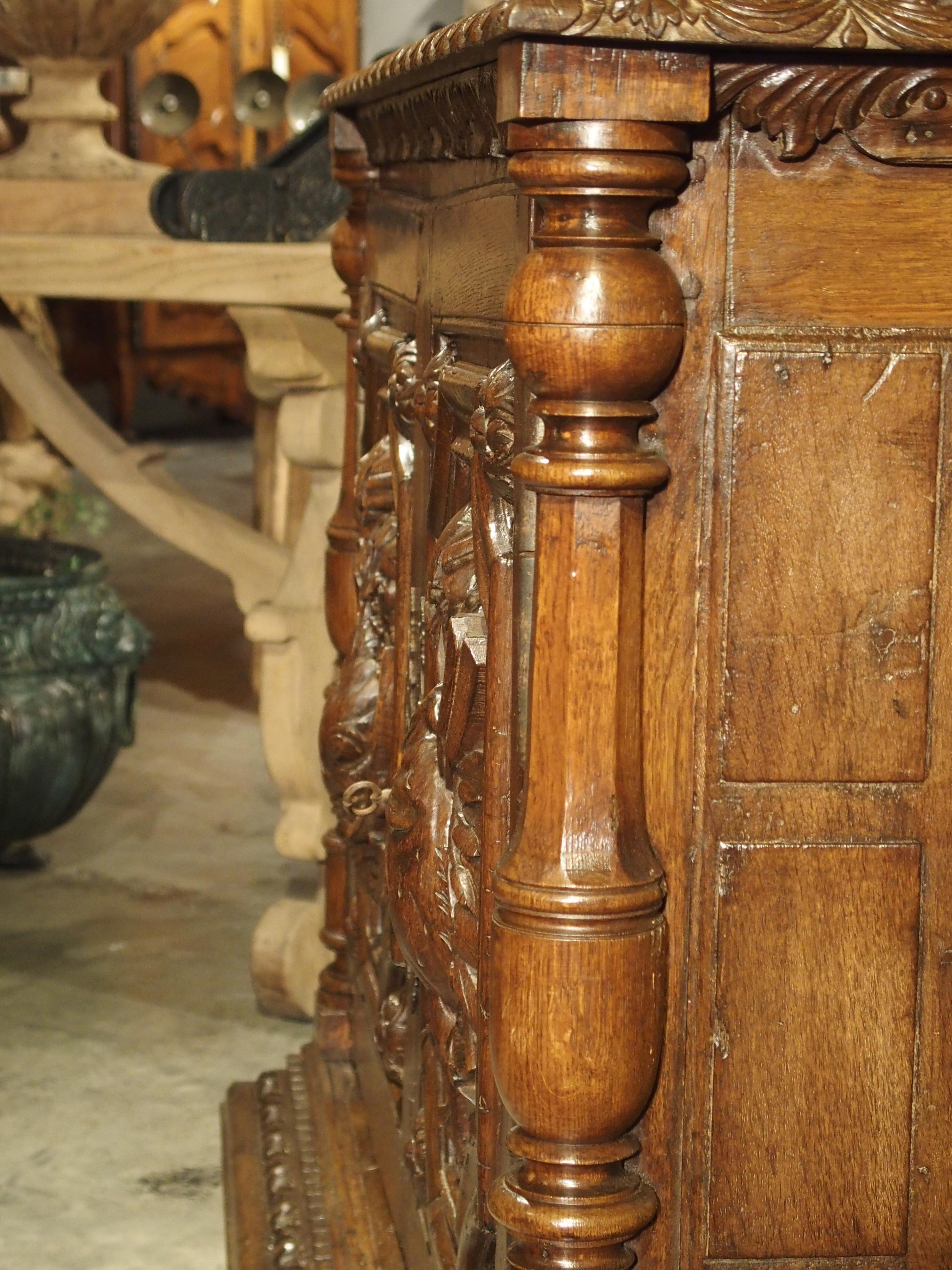 From the 1700s, this unusual French hunt buffet has expertly carved paneled doors portraying a game bird and a fish. The game bird is hanging from its feet with knotted ribbons, while the fish hangs by a hook, also from knotted ribbons. Both are