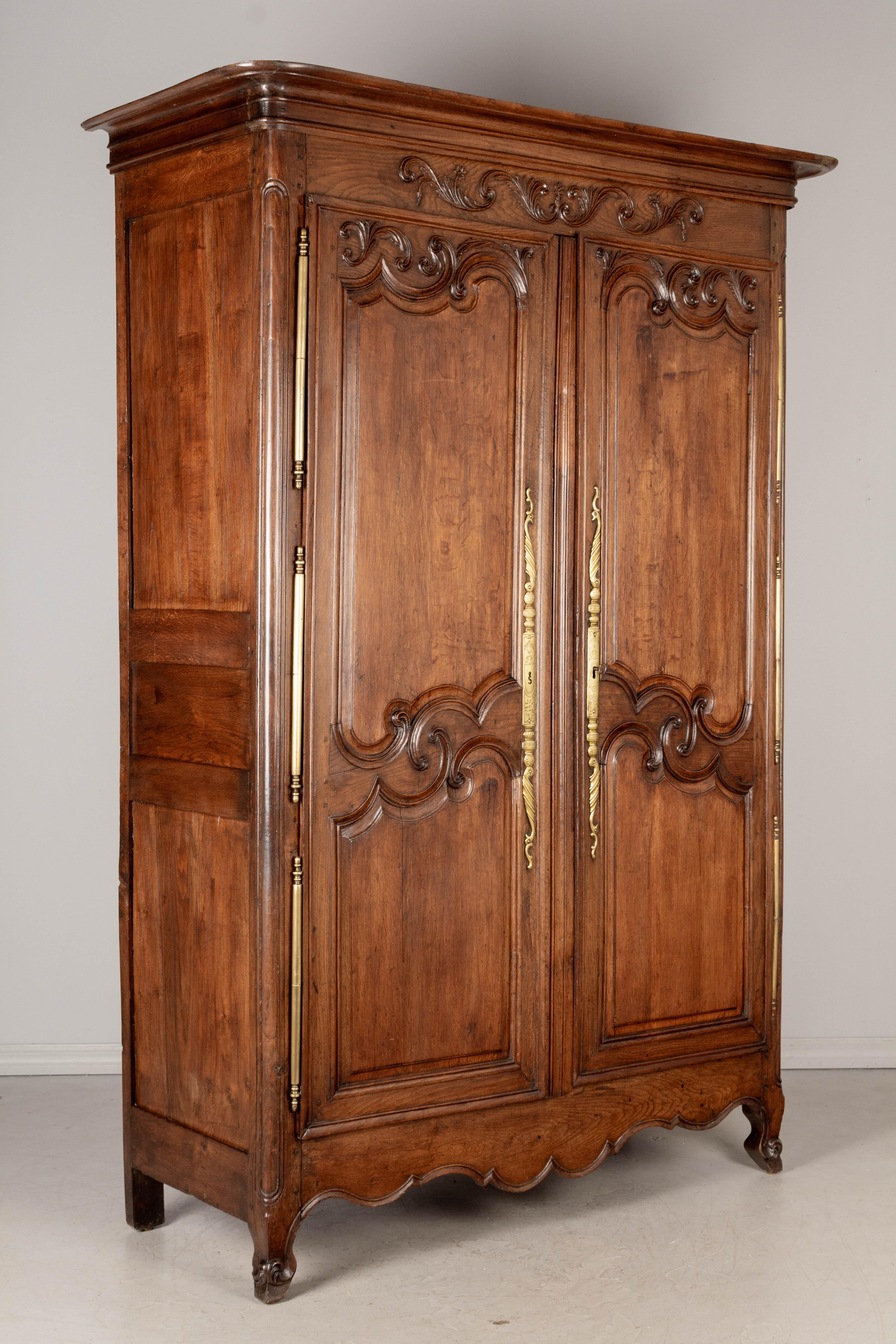 An 18th century French armoire from Normandy made of solid oak with nice had carved details. Original brass hardware with working lock and key. Interior has one original shelf with three drawers and two new shelves. Waxed patina. Normal minor