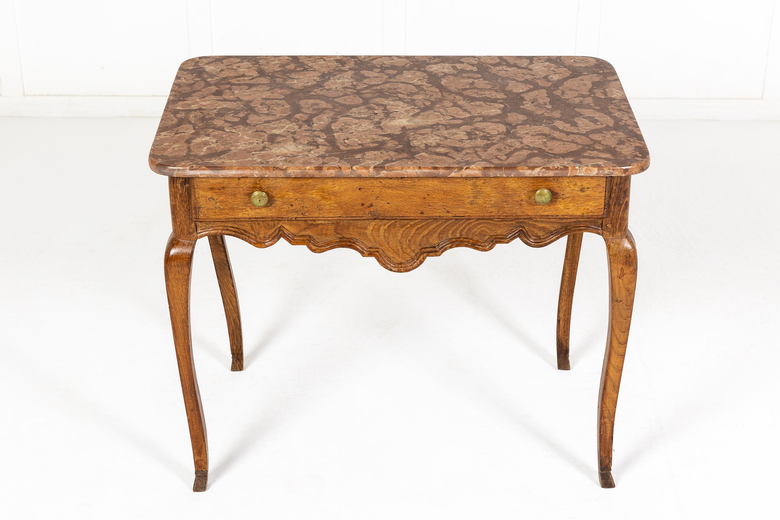 18th century French oak side table with a stunning fossil marble top. A single drawer with brass knob handles above a carved and moulded apron. Supported by elegant, slender cabriole legs.