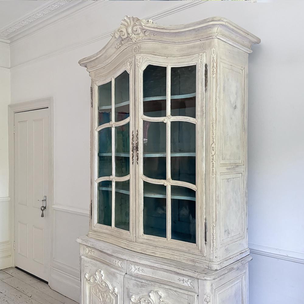 Un'elegante vetrinetta francese d'epoca realizzata in legno massiccio di quercia, con motivi di conchiglie splendidamente intagliate e linee serpentine dolcemente curve che catturano la raffinatezza del design francese del XVIII secolo. Il mobile