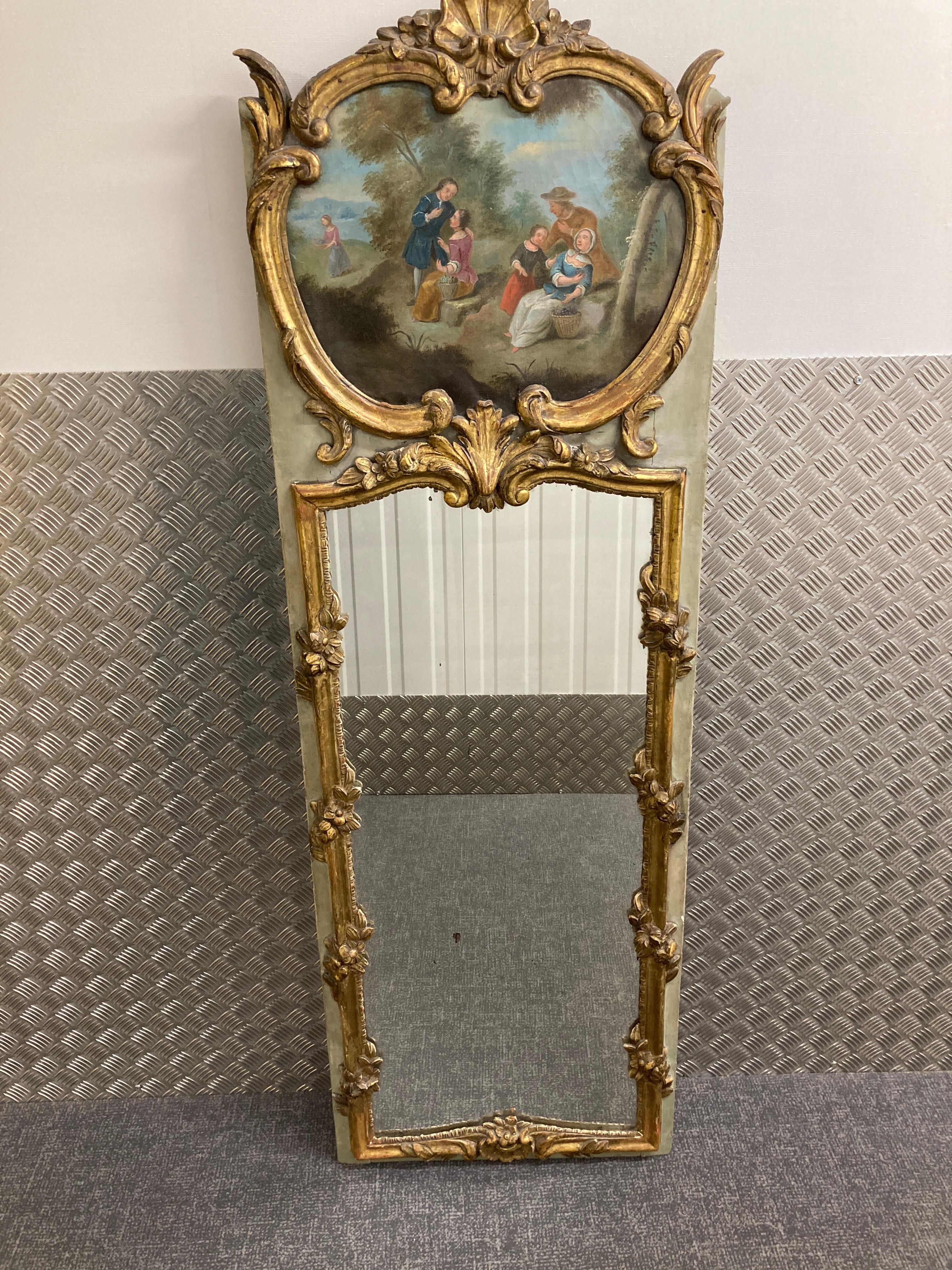 18th Century French Painted and Parcel-Gilt Trumeau Mirror.
The upper section with a romantic oval painted panel of fruit pickers in a cartouche shaped frame with a shell crest, over an oblong original mirror plate within a flower entwined slender
